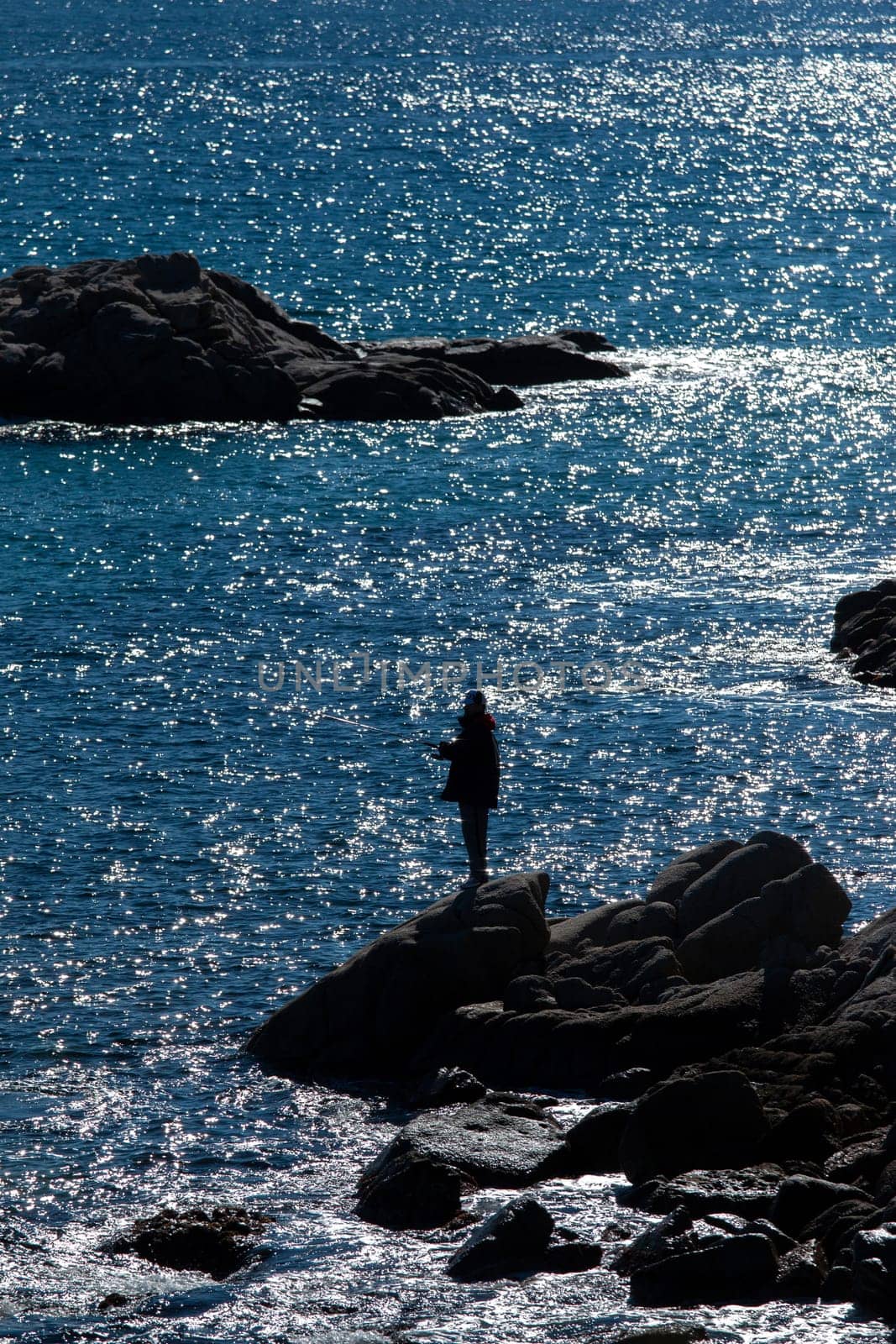 Silhouette of man fishing on mediterranean sea, in Costa Brava of Spain, at sunset.