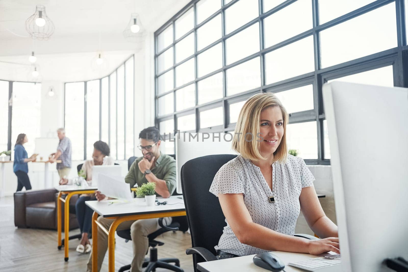 Having access to the right tools makes work more fun. a designer working on her computer at her desk. by YuriArcurs