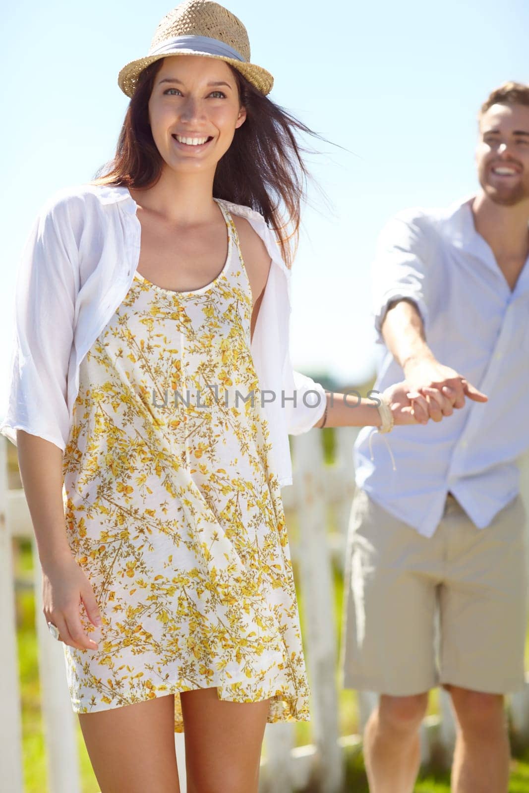 Couple, hands and smile for happy summer vacation, travel or journey together in the outdoors. Beautiful woman leading her boyfriend by the hand on a warm sunny day for the holiday in nature.