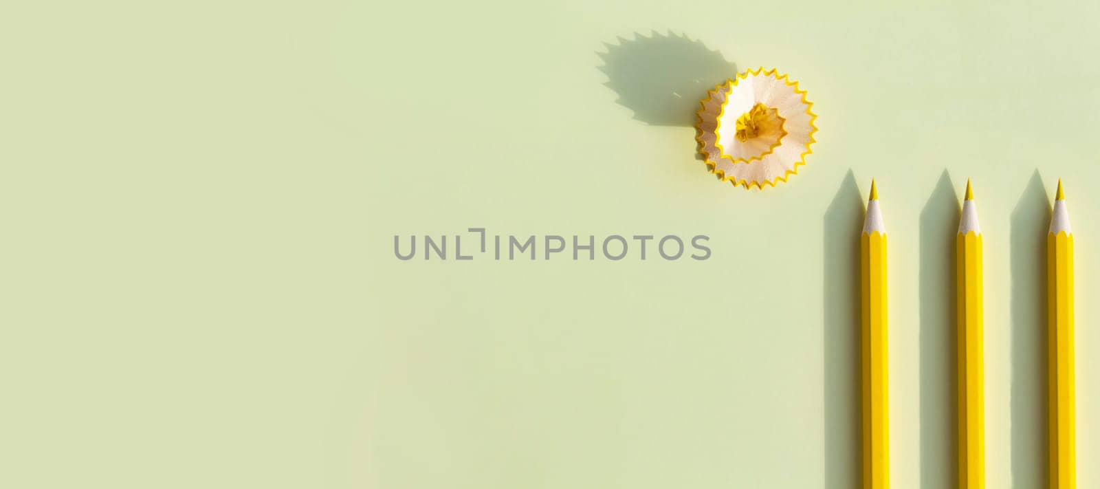 Yellow pencil with bright shavings and cleans on a yellow background. Advertising banner by Alla_Yurtayeva