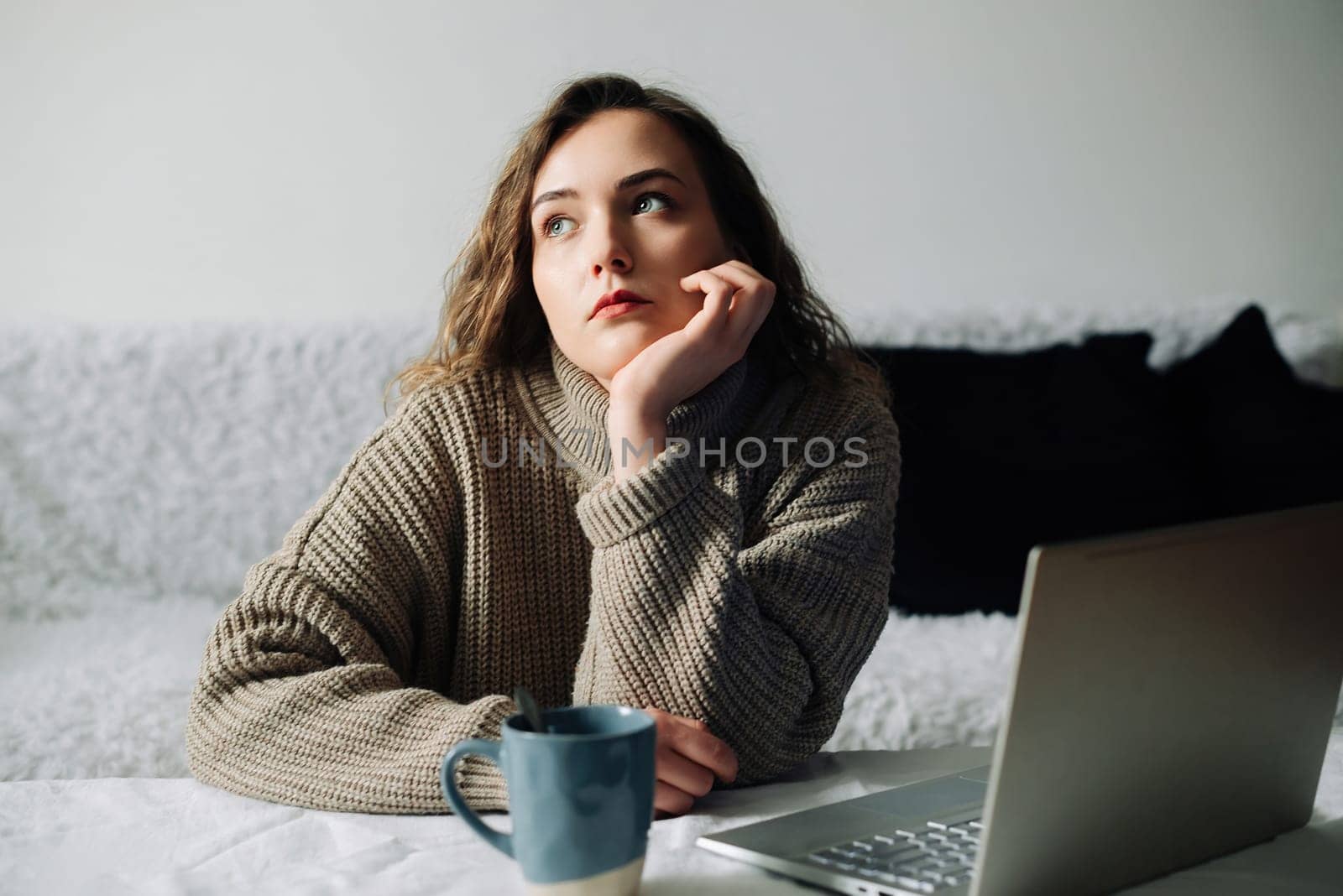 Creative woman working from home writing lesson plan and schedule for students, using laptop and sipping coffee at kitchen table. Productive teacher writes outline and schedule at laptop.