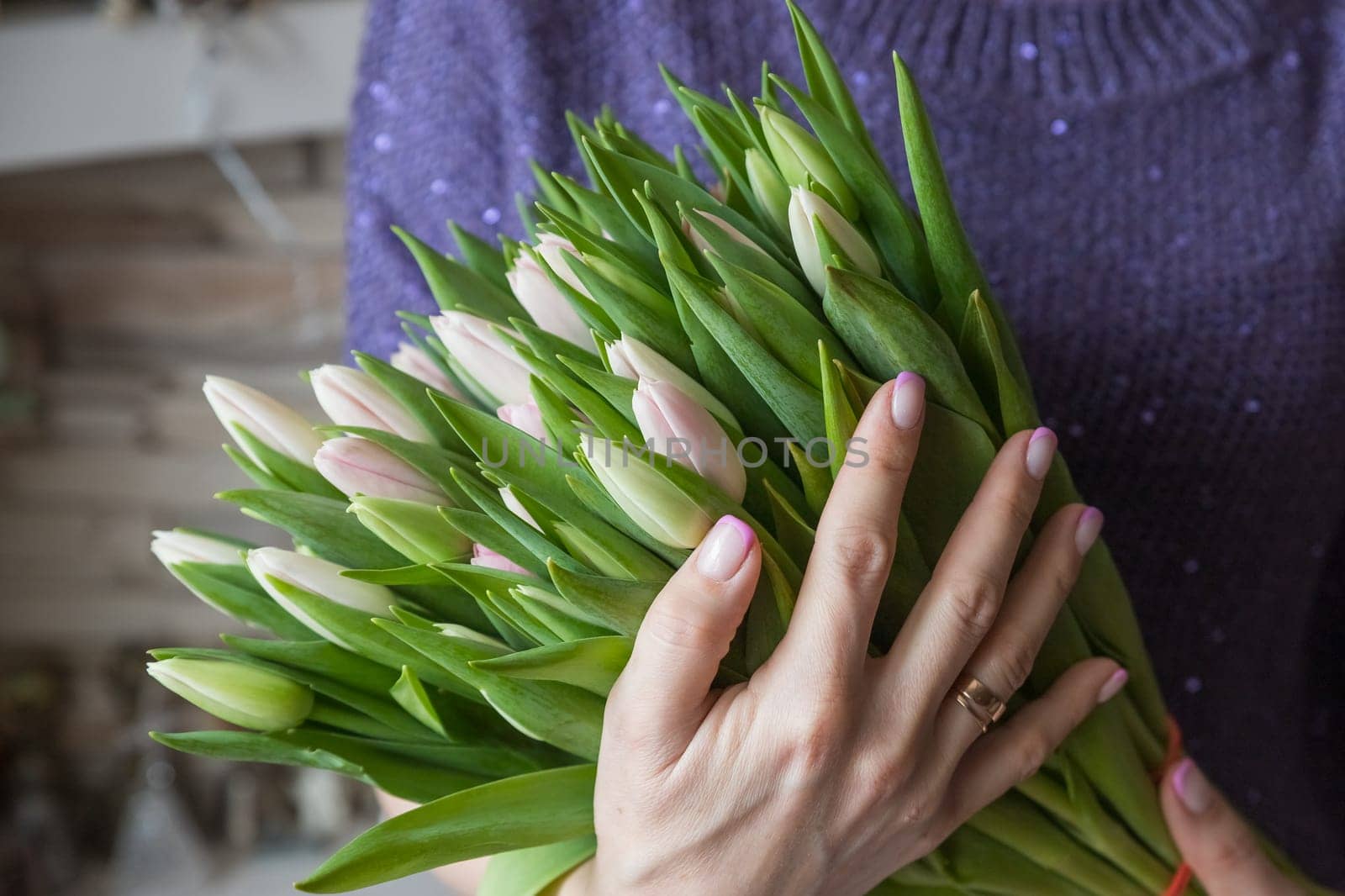 Very nice young woman standing outdoors, holding big and beautiful bunch of fresh red tulips, cropped photo, bouquet close up