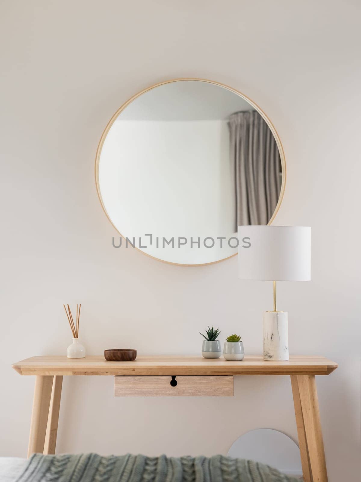 Close-up of a wooden table and a frame with mirror with stylish accessories in a young womans bedroom. The concept of stylish minimalist interior design in a new apartment. Copyspace by apavlin