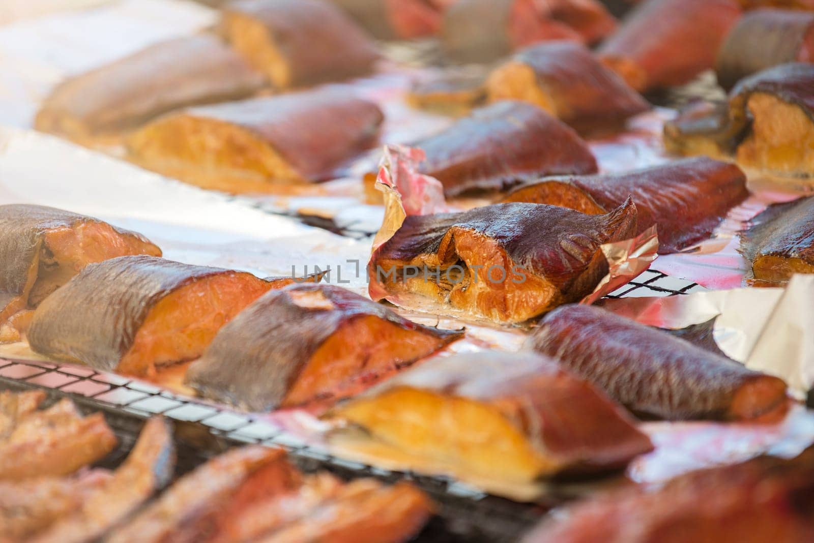 Hot smoked salmon. Large pieces of Atlantic salmon are smoked on a smokehouse grate close-up. Fish smoking plant. High quality photo