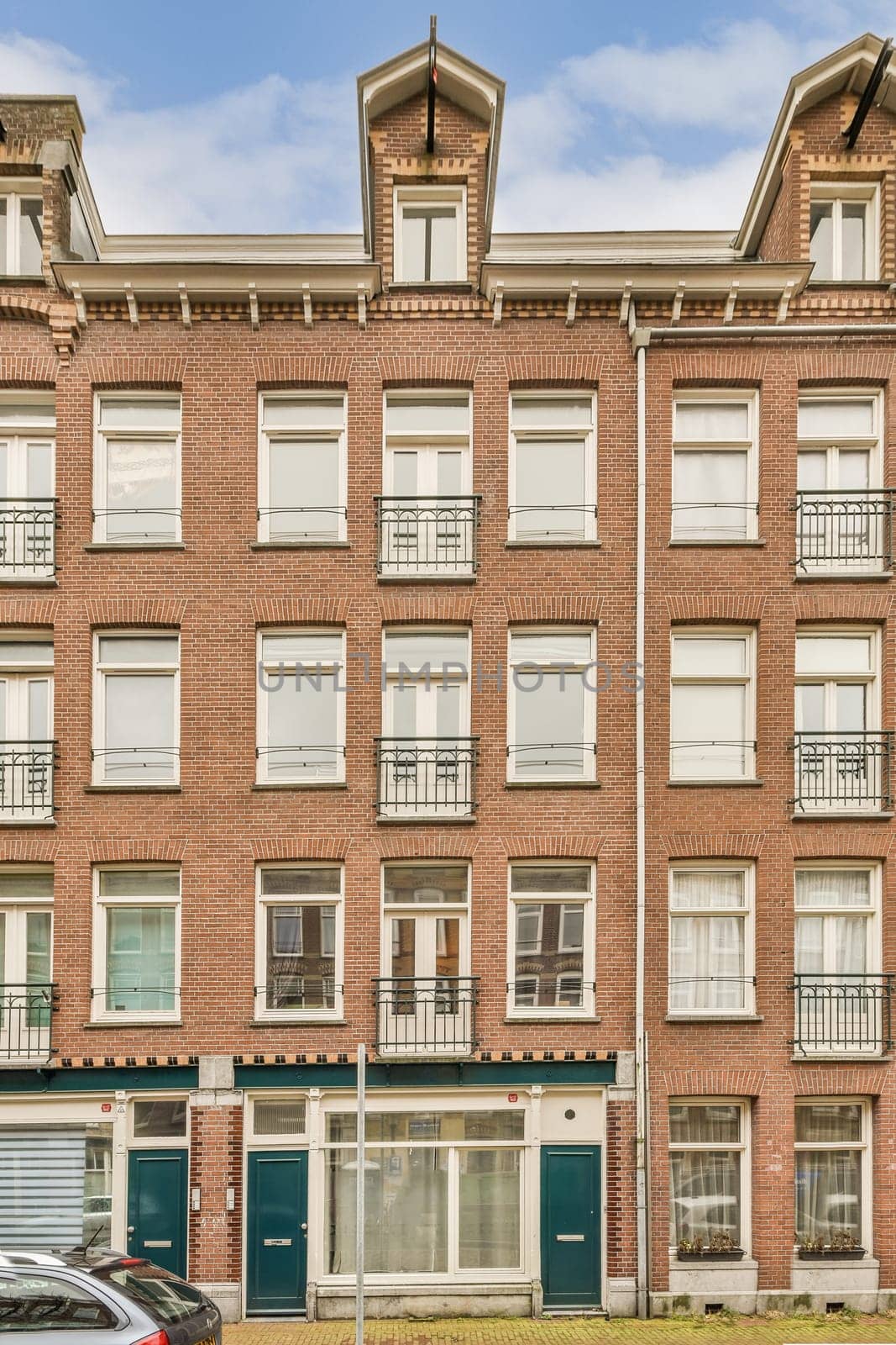 an apartment building with cars parked on the street next to it and two buildings in the background are red brick