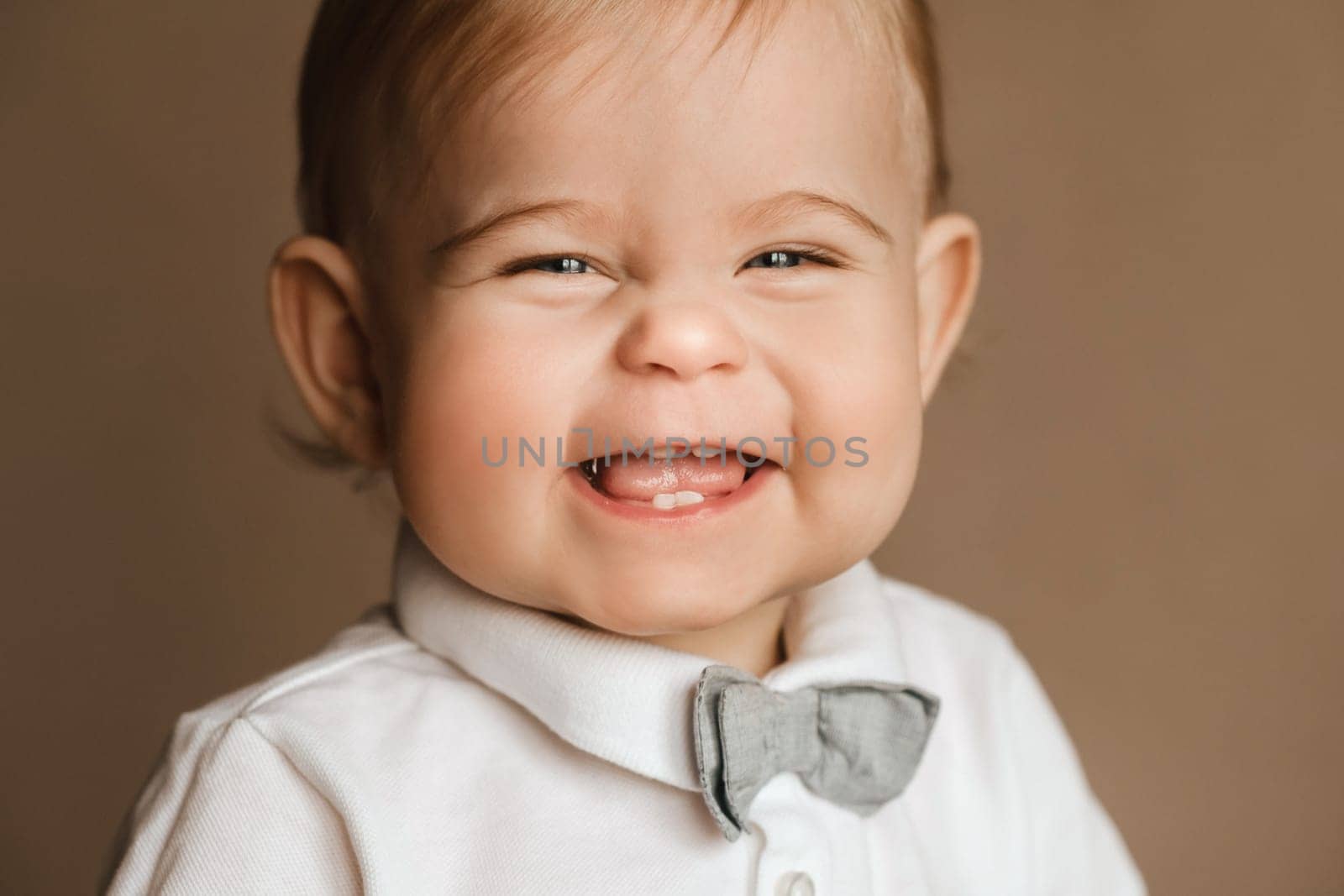 Portrait of a cheerful little boy in a white shirt with a bow tie by Lobachad