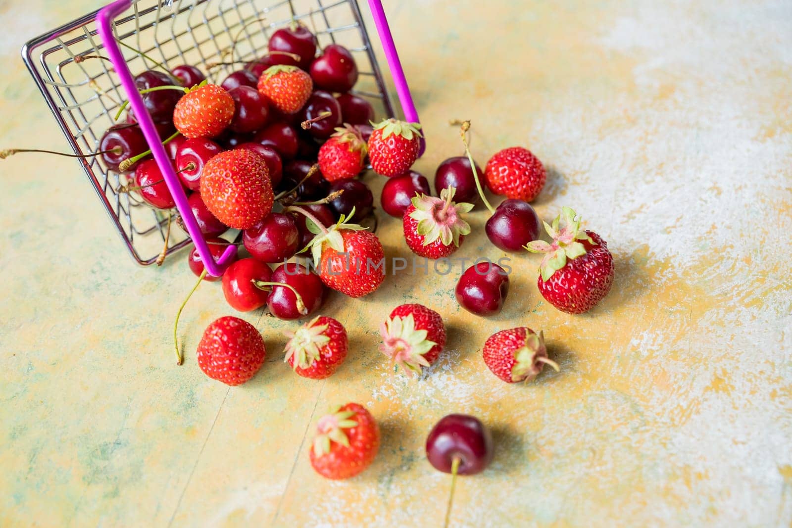Fresh red fruit and berries - cherries, peaches and strawberries - in supermarket cart tray on black background. Copy space