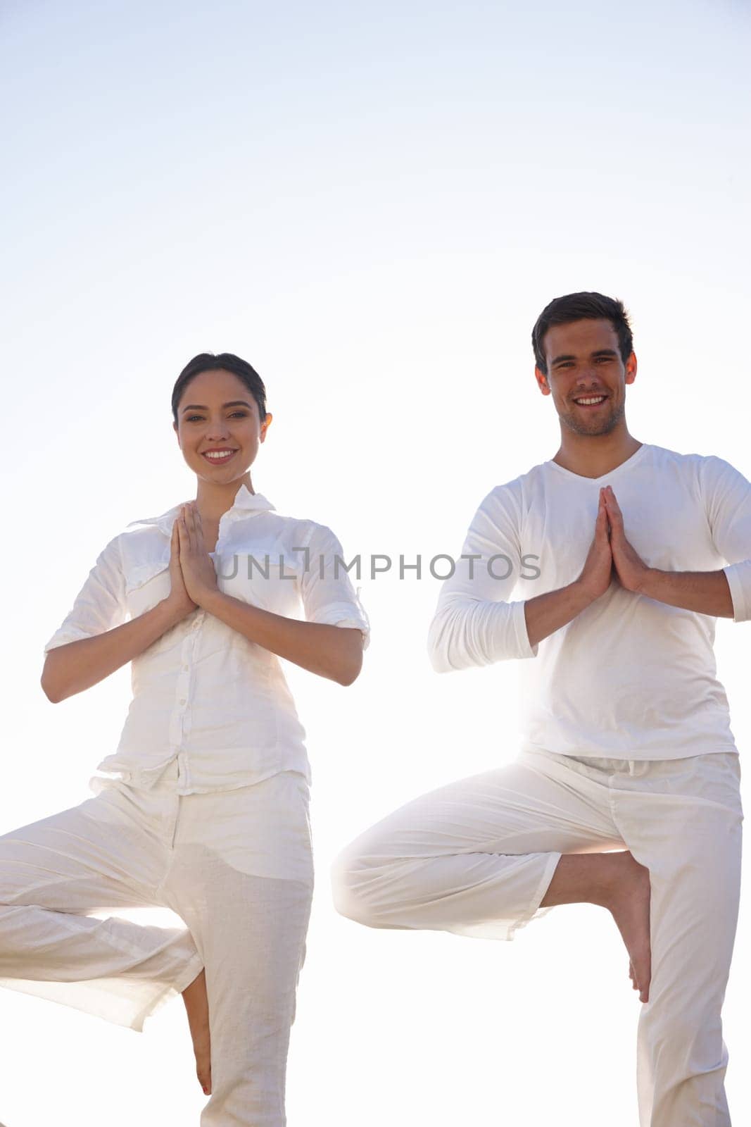 Yoga stances that improve balance. a young man and woman doing yoga outdoors. by YuriArcurs