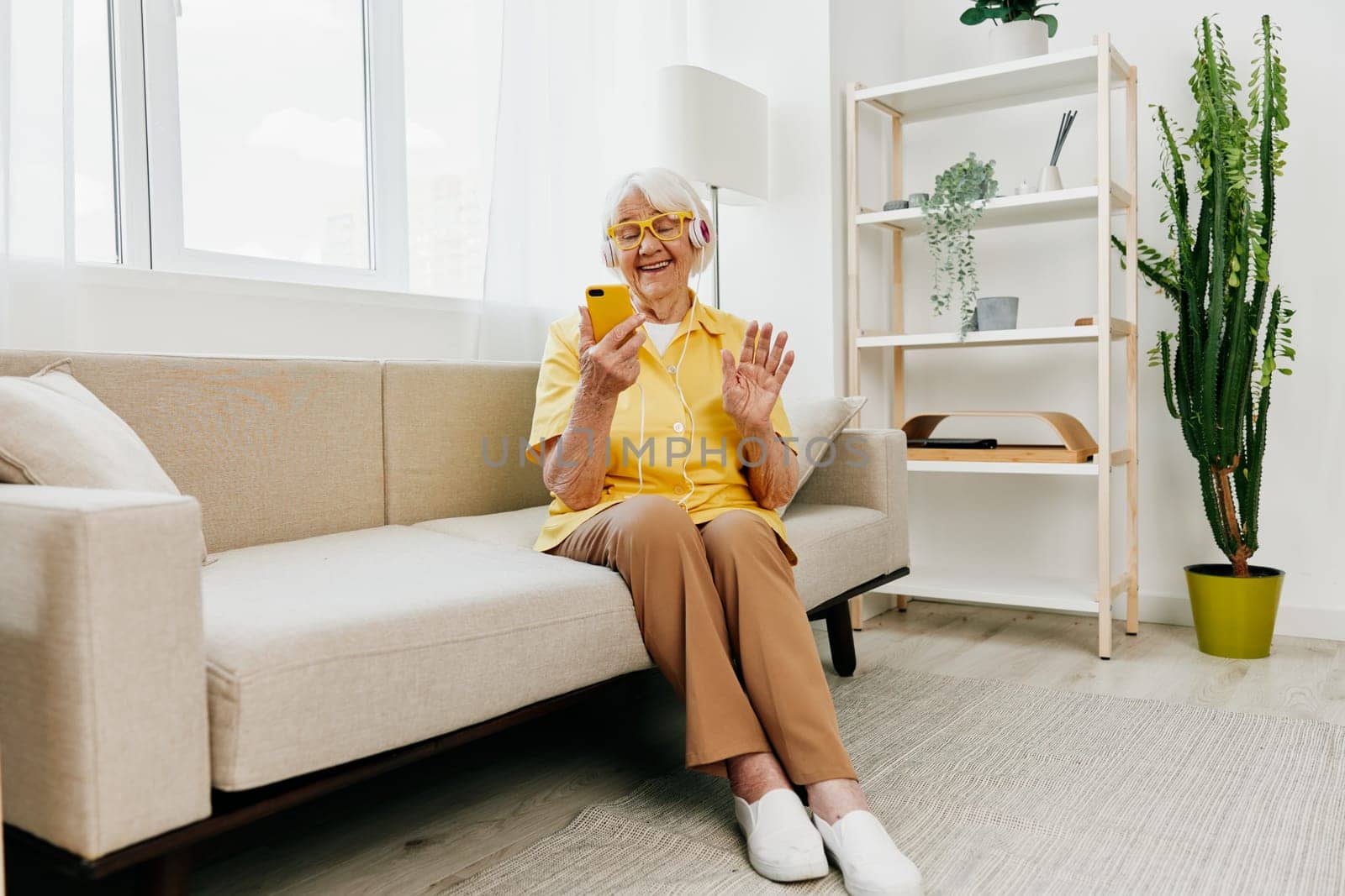Happy elderly woman looking into phone video call smile, technology for communication, bright modern interior, lifestyle online communication. by SHOTPRIME