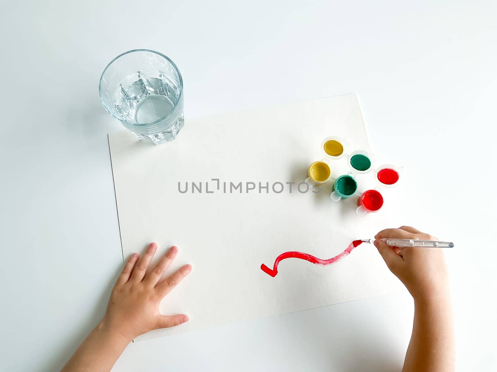 small child draws with paints and brush on white table. fathers day. High quality photo