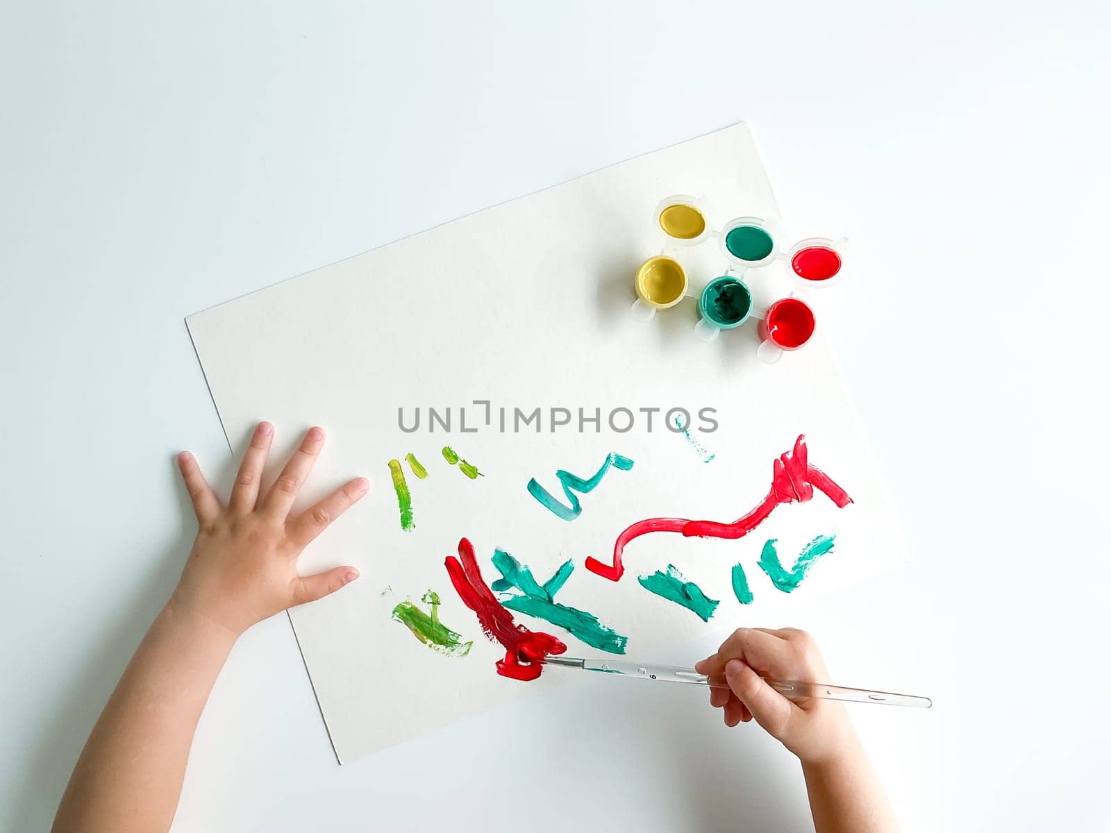 small child draws with paints and brush on white table. fathers day. High quality photo