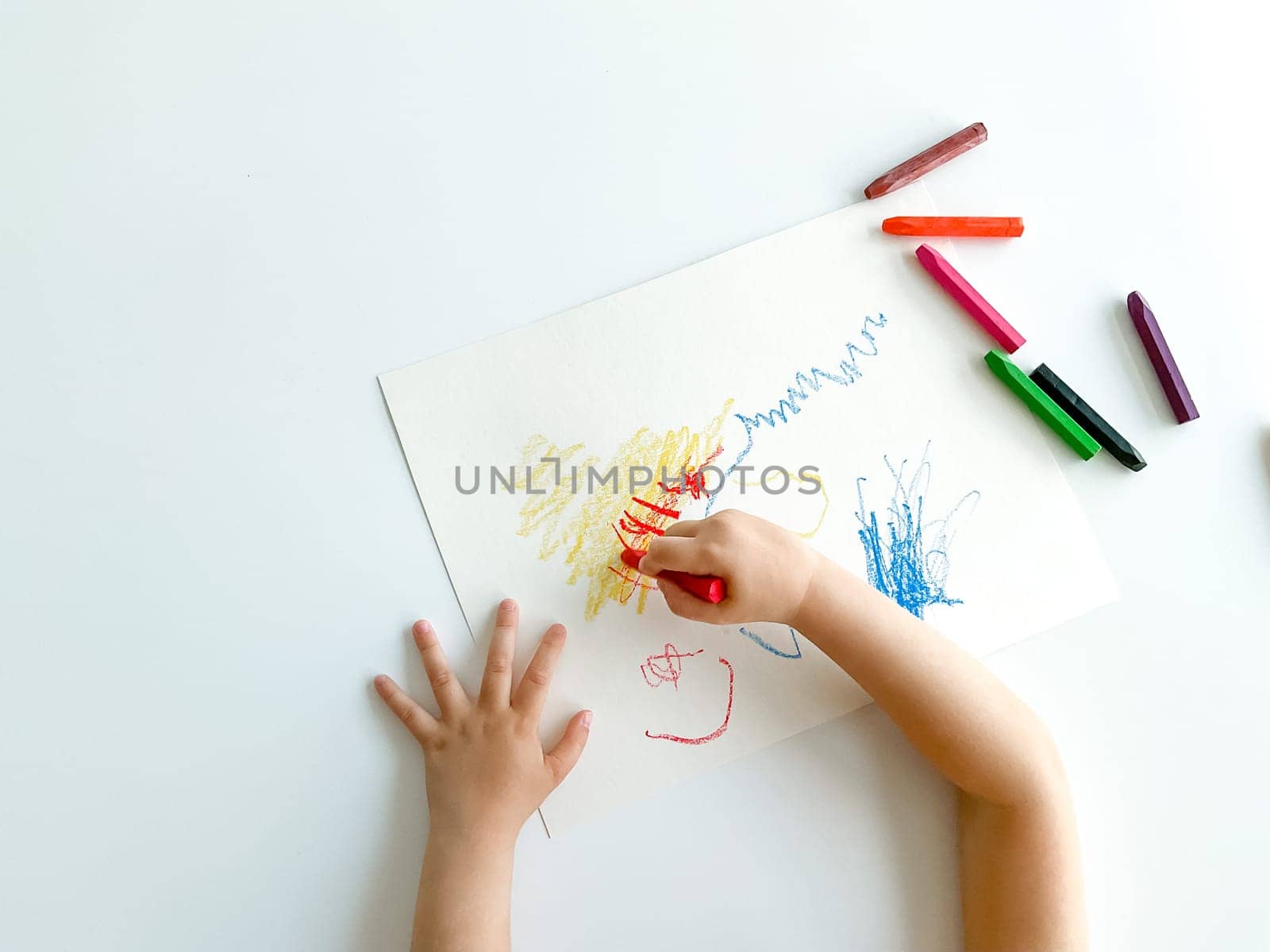 small child draws with pastel crayons on white table. fathers day. High quality photo