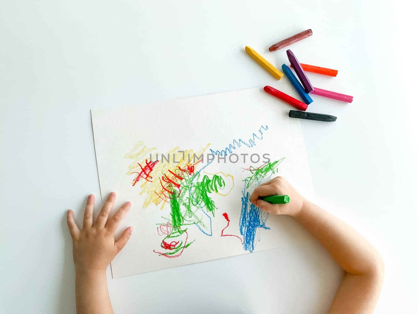 small child draws with pastel crayons on white table. fathers day. High quality photo