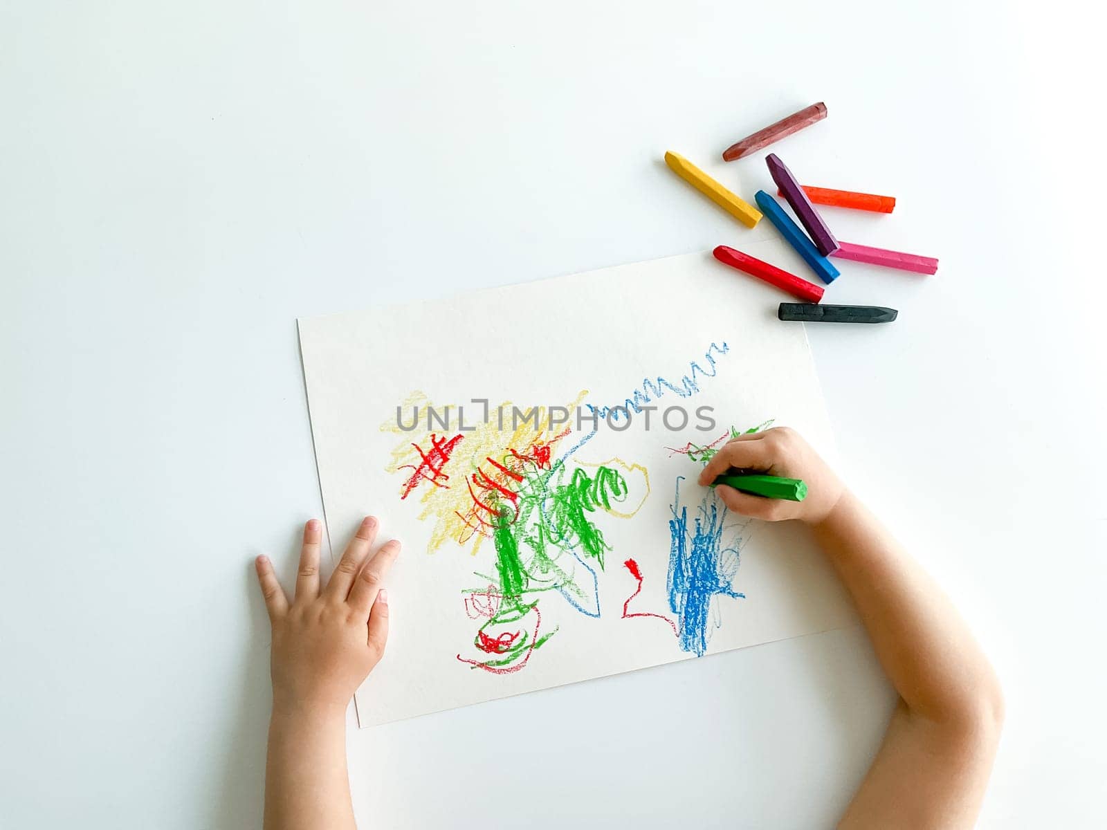 small child draws with pastel crayons on white table. fathers day by Lunnica