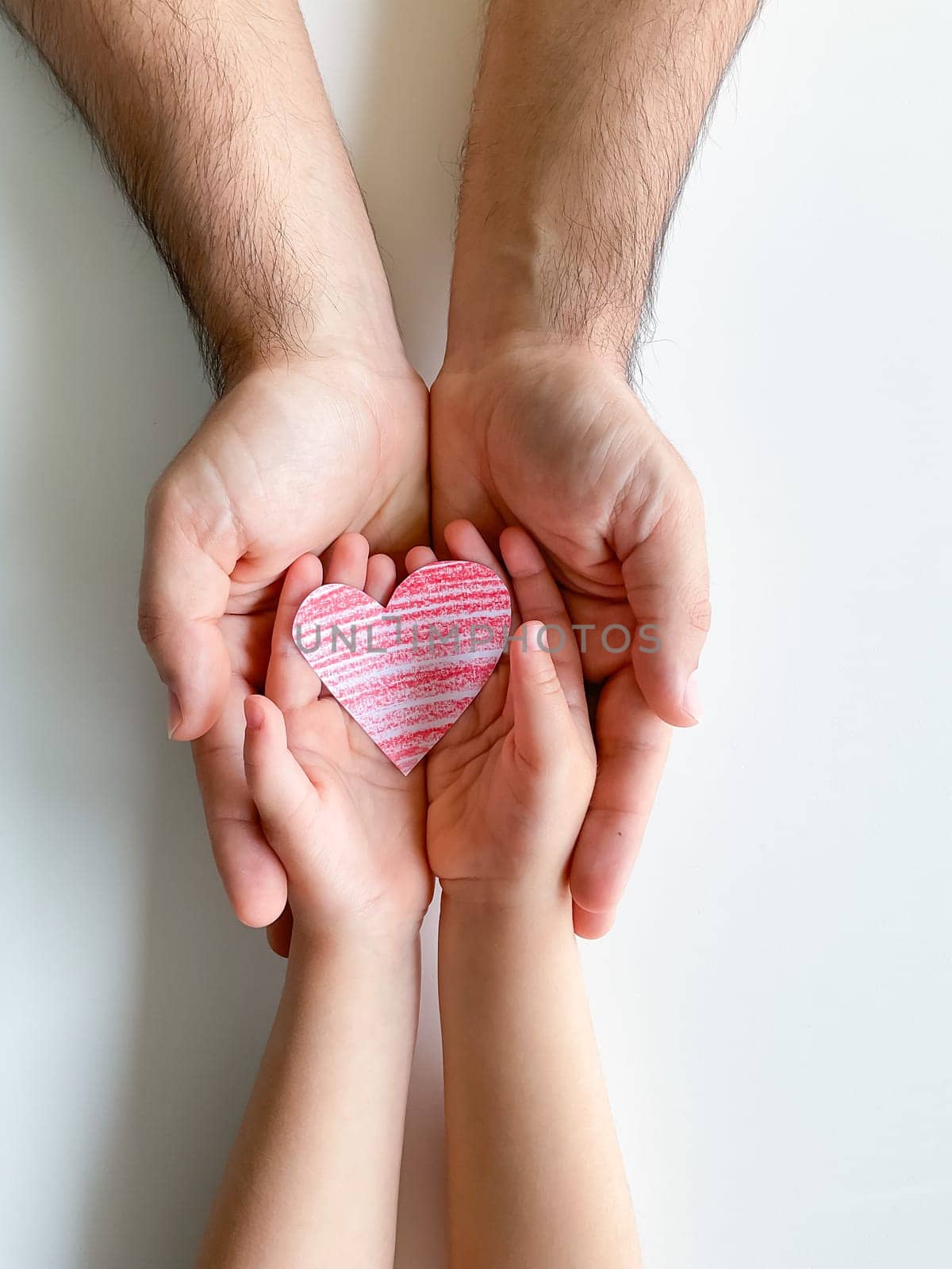 adult and childrens hands hold small red paper heart. Fathers Day. Family, love by Lunnica