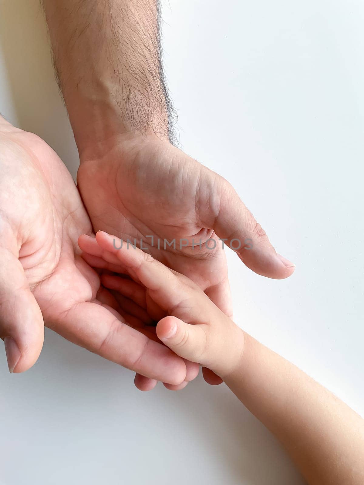 An adult and a child hold their hands together. Fathers Day. A child gives a hand to an adult. Postcard concept