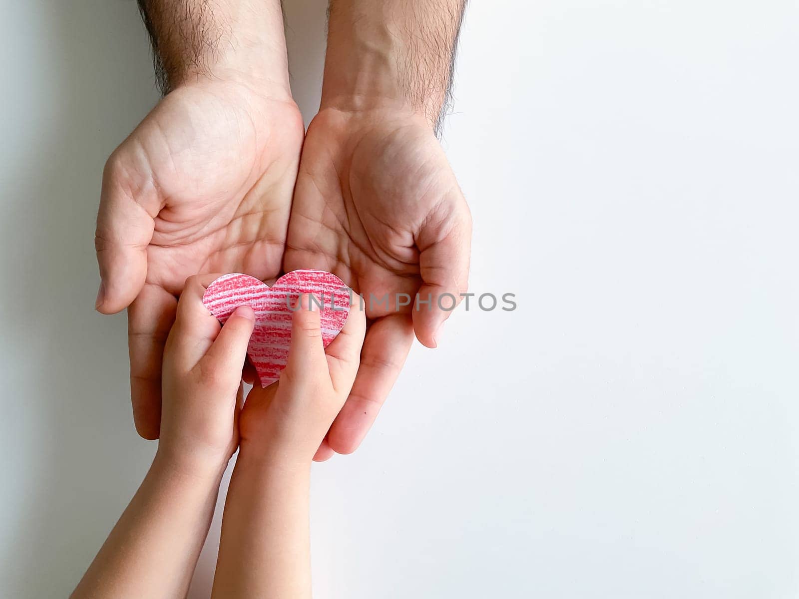 child gives adult a small red paper heart. Fathers Day. Family, love, parents, children, care, tenderness