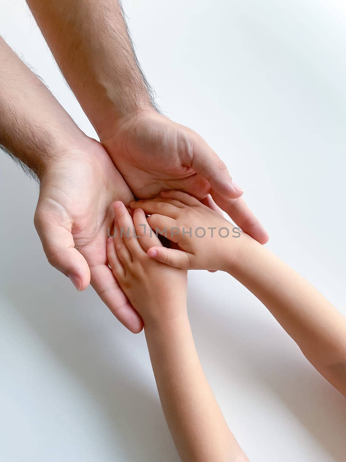 Adult and child hold their hands together. Fathers Day Child gives hand to adult by Lunnica