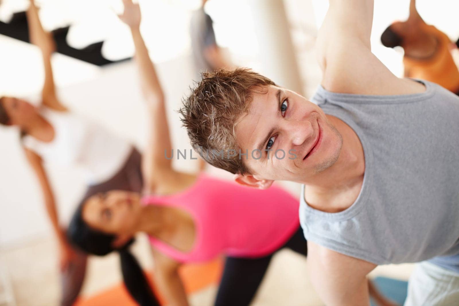 Yoga is not exclusively for women. A young man smiling at the camera in yoga class. by YuriArcurs