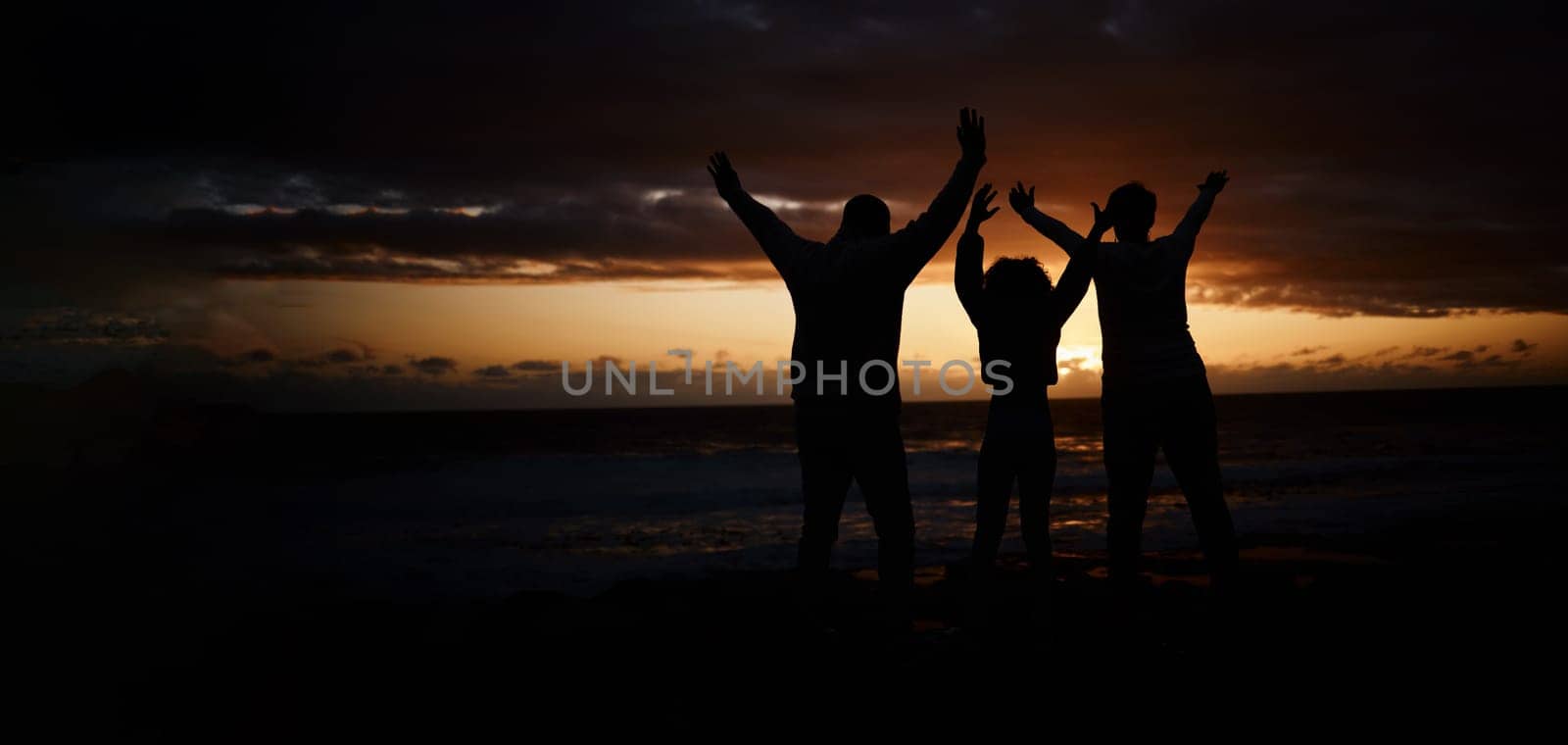 Freedom, sunset and silhouette of a family at the beach while on a summer vacation or weekend trip. Adventure, carefree and shadow of people by the ocean together while on a seaside travel holiday