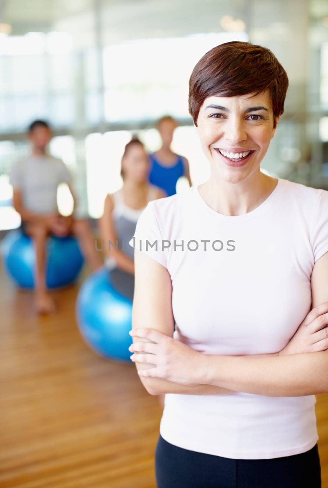 Woman in fitness club. Portrait of fitness trainer with people practicing yoga in background