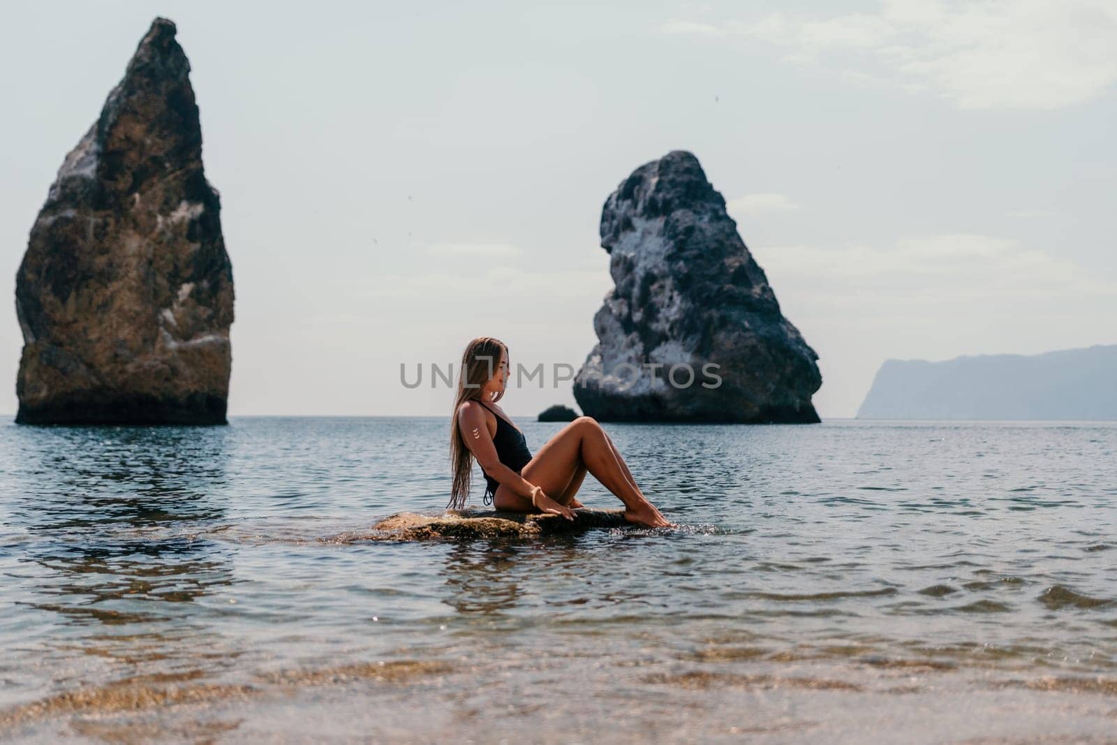 Woman travel sea. Young Happy woman in a long red dress posing on a beach near the sea on background of volcanic rocks, like in Iceland, sharing travel adventure journey