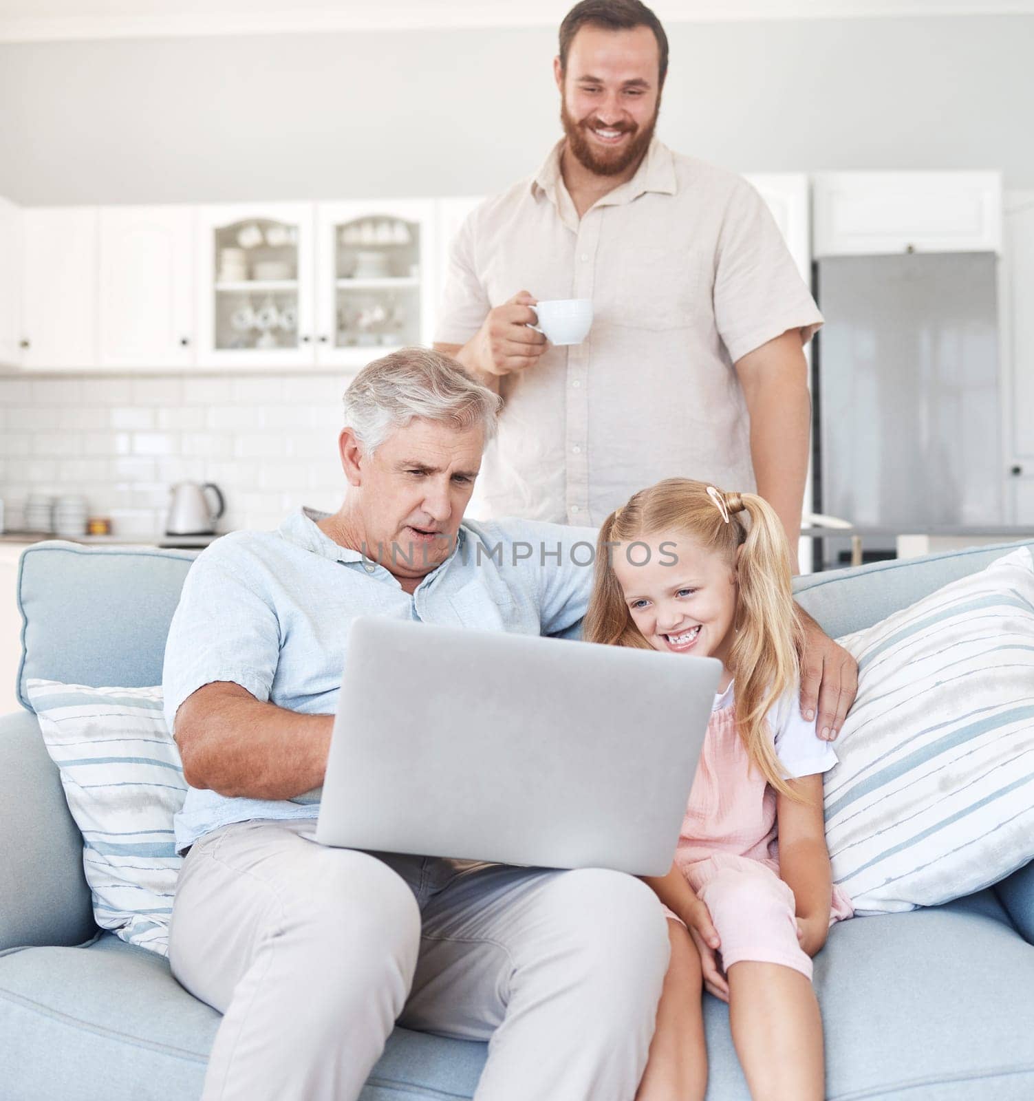 Family, laptop and girl relax with grandfather on sofa while father drinking coffee in the background, happy, cheerful and sweet. Love, happy family and online streaming by grandpa and child smiling.