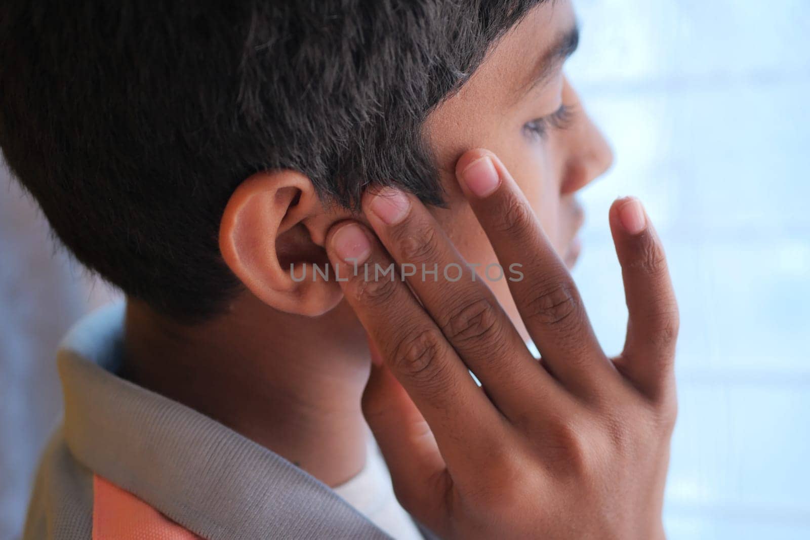 teenage boy having ear pain touching his painful ear