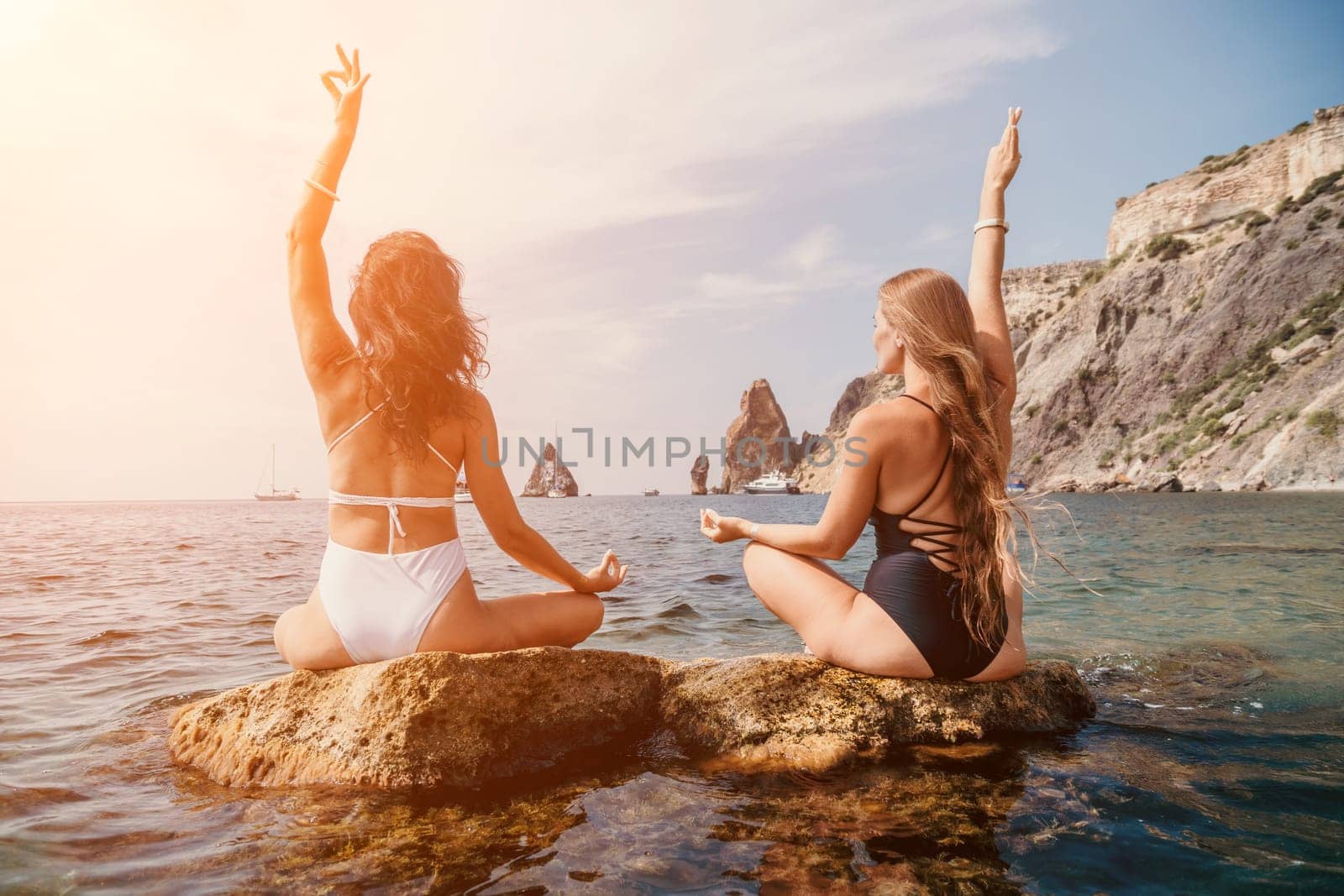 Woman sea yoga. Back view of free calm happy satisfied woman with long hair standing on top rock with yoga position against of sky by the sea. Healthy lifestyle outdoors in nature, fitness concept.