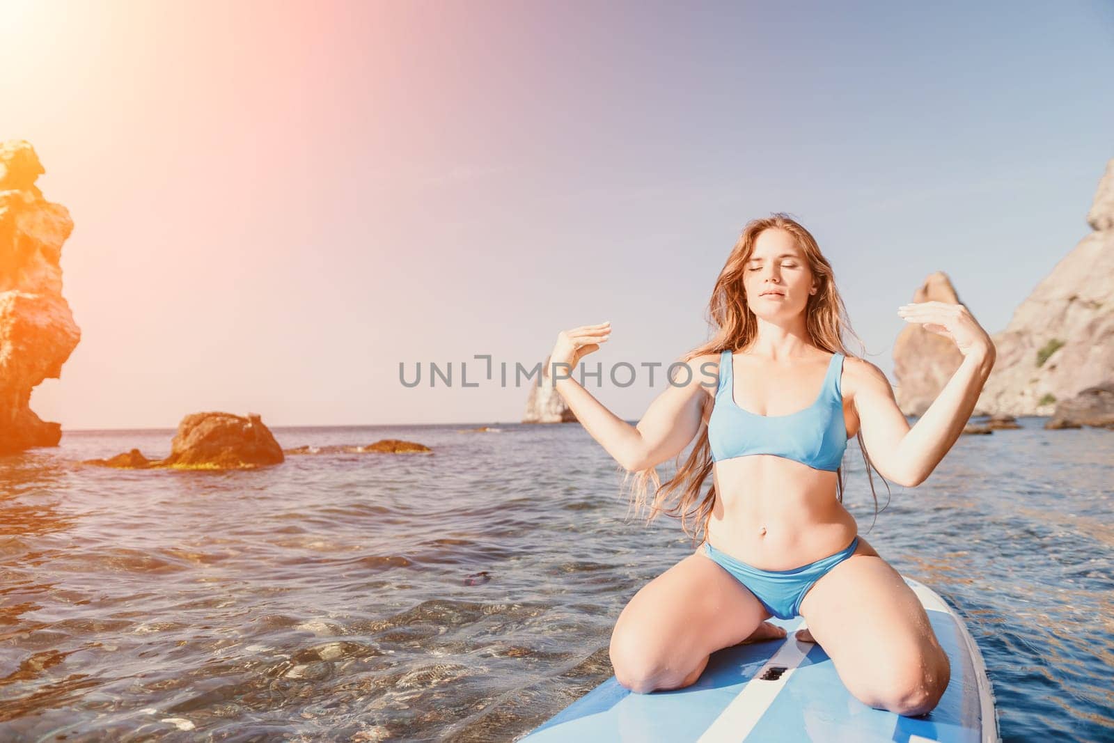 Close up shot of happy young caucasian woman looking at camera and smiling. Cute woman portrait in bikini posing on a volcanic rock high above the sea