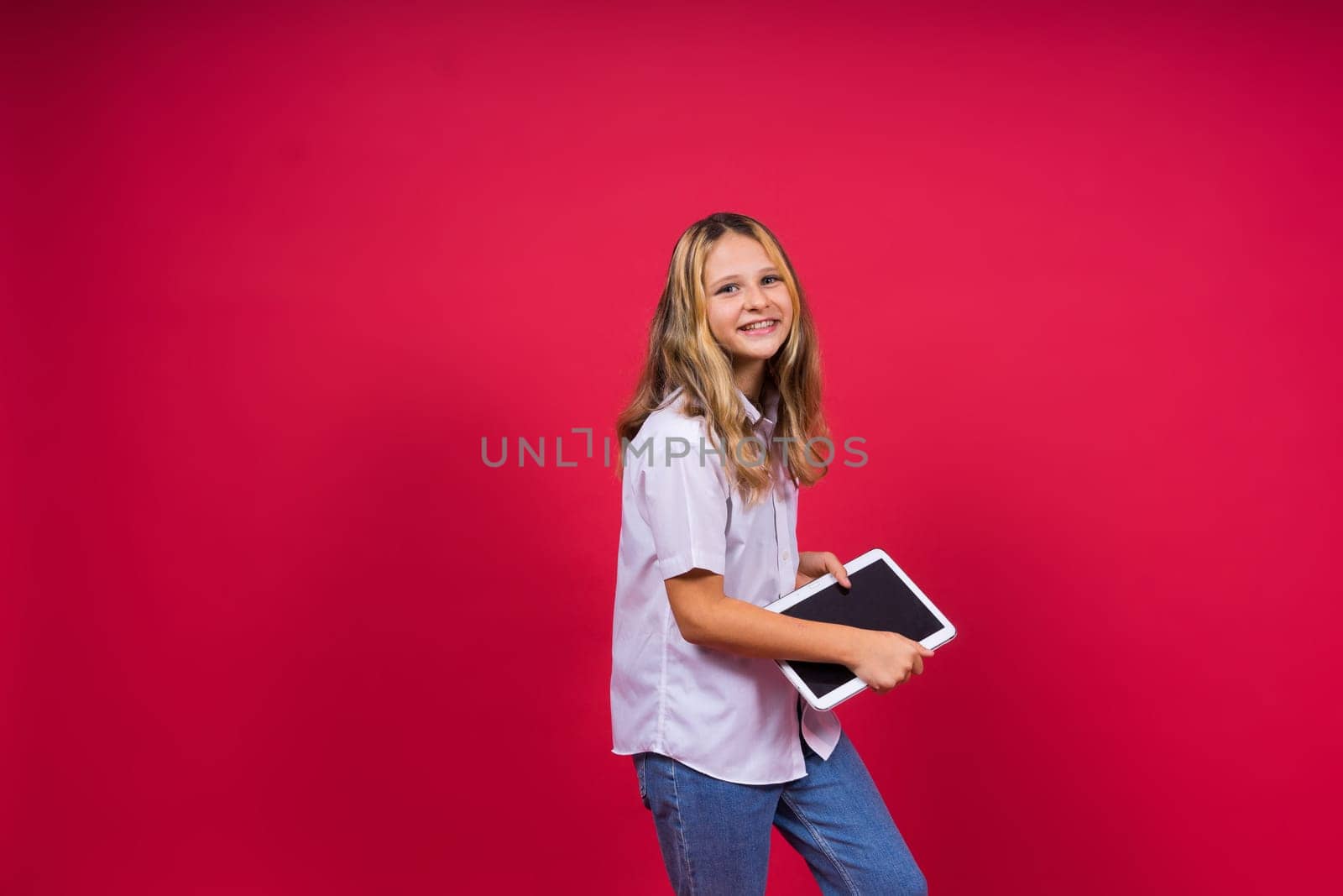 Online school app. Schoolgirl showing tablet computer Empty Screen Over red Background. Studio Shot by Zelenin