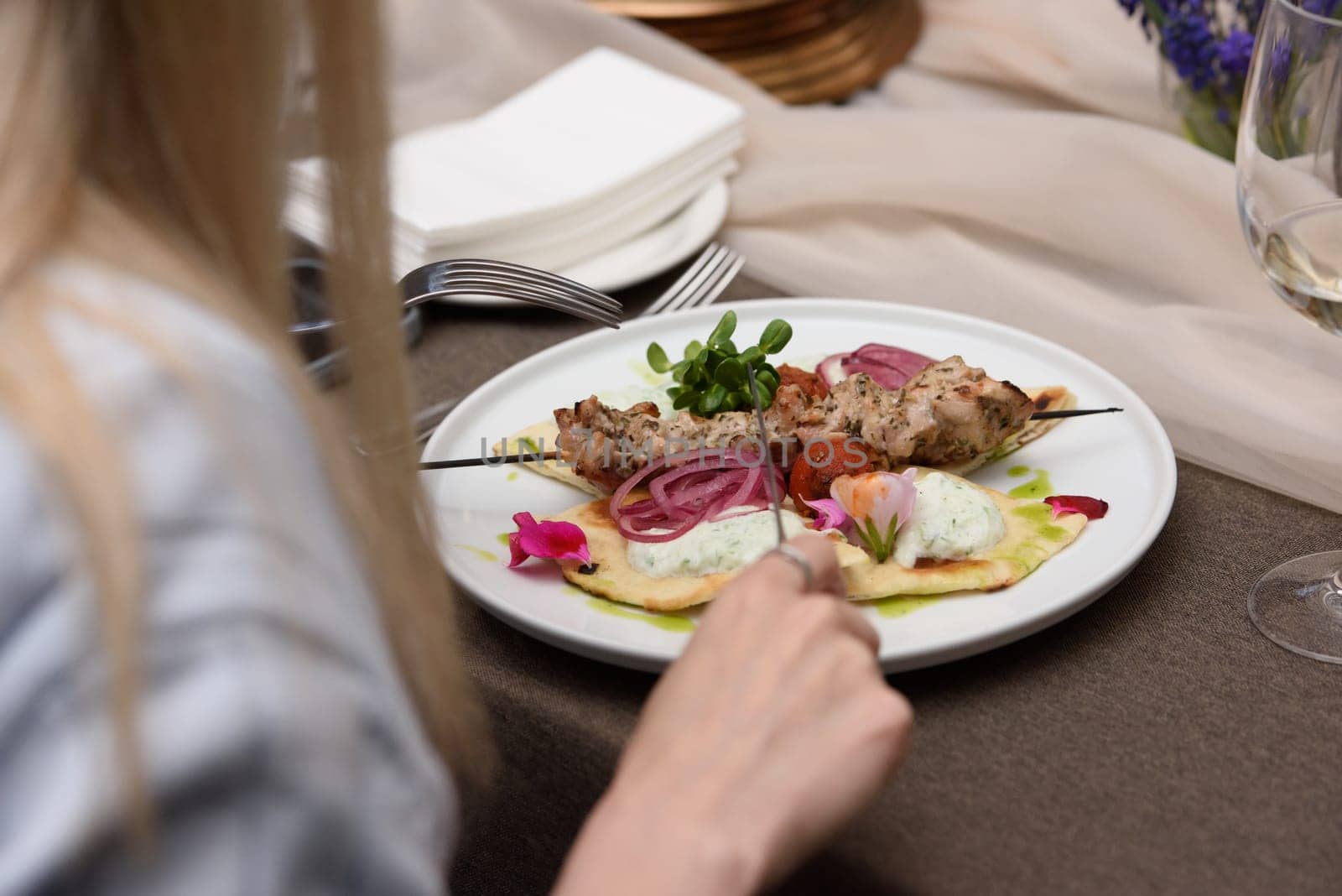 woman eats in a restaurant souvlaki with pita and tzatziki sauce by Ashtray25