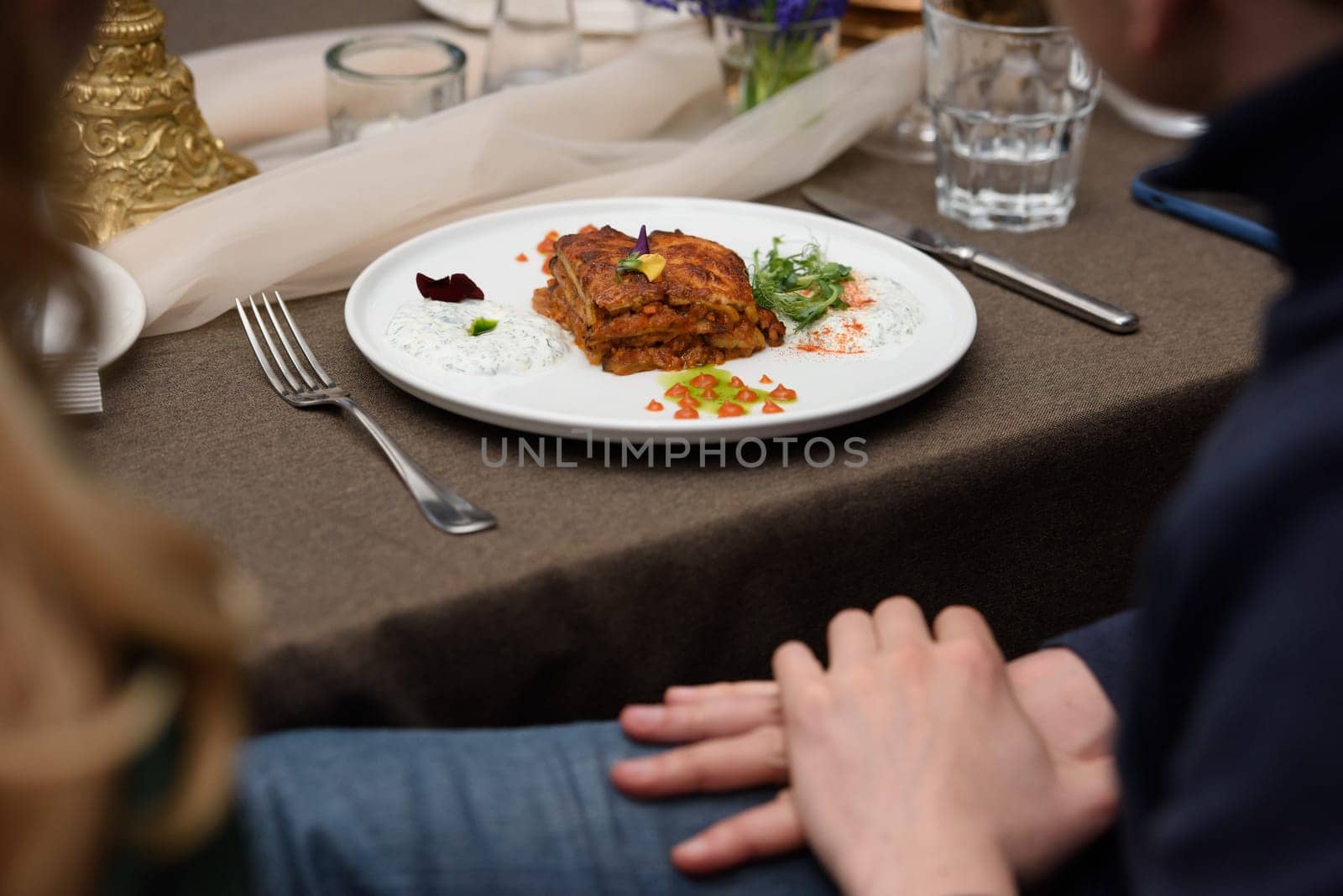 portion of traditional greek moussaka in white plate on a table in a restaurant by Ashtray25