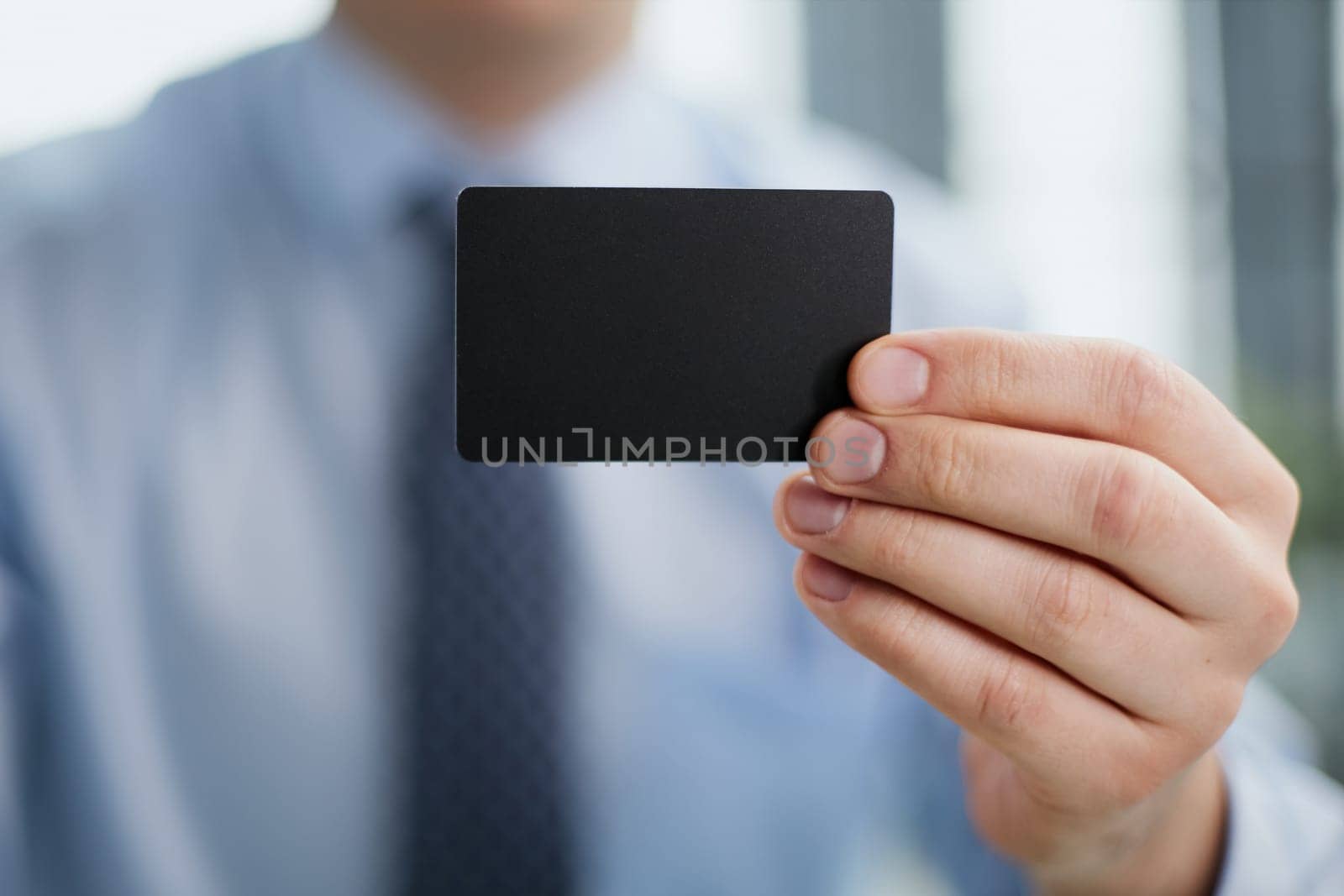 A man holds a black business card. A paper in the hands of a man.