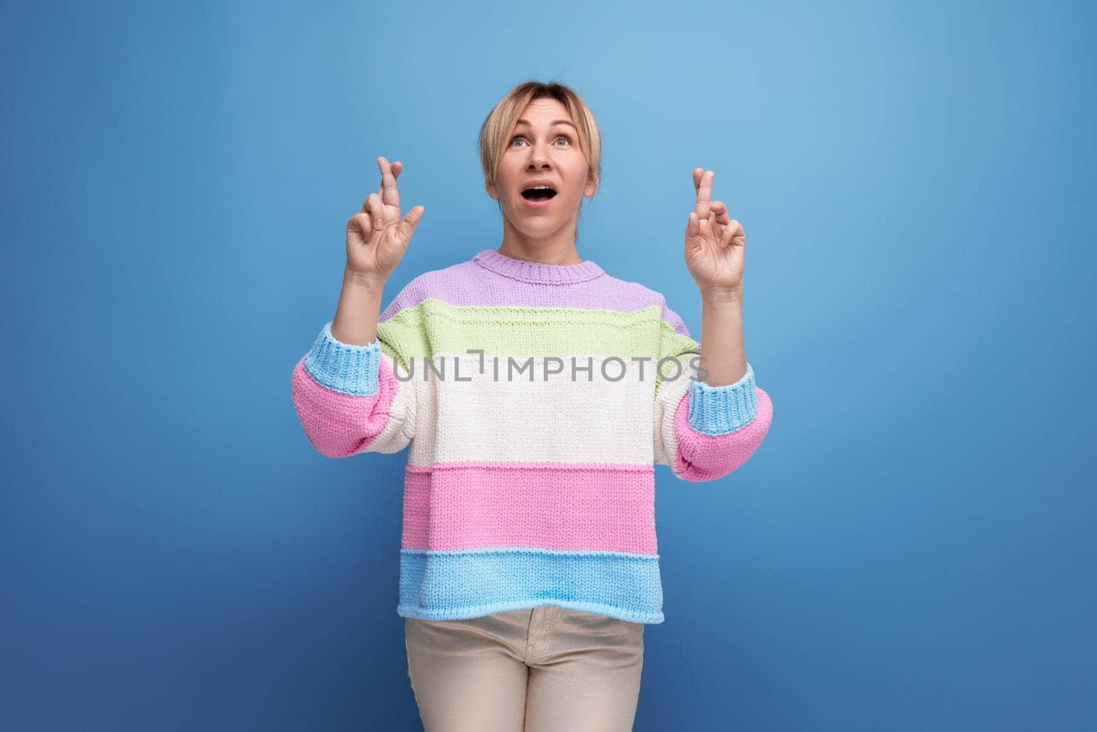 surprised blond woman in casual outfit showing hands up on blue background with copy space by TRMK