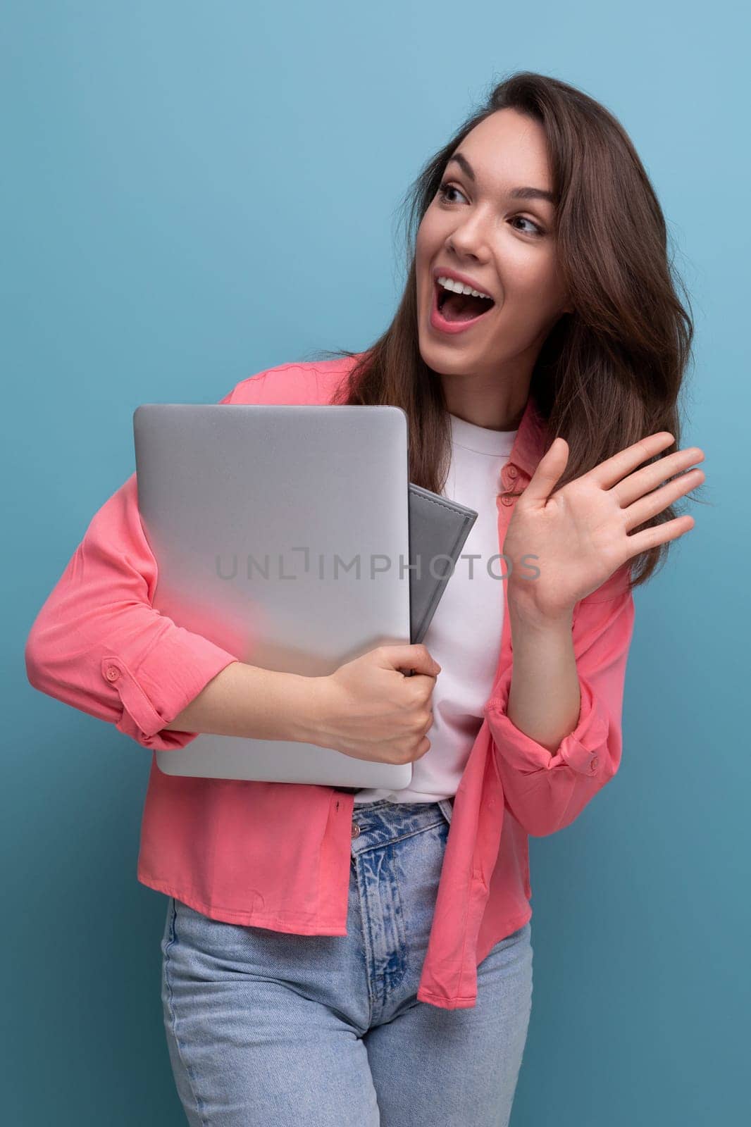 positive successful freelance brunette young woman in shirt and jeans with laptop.