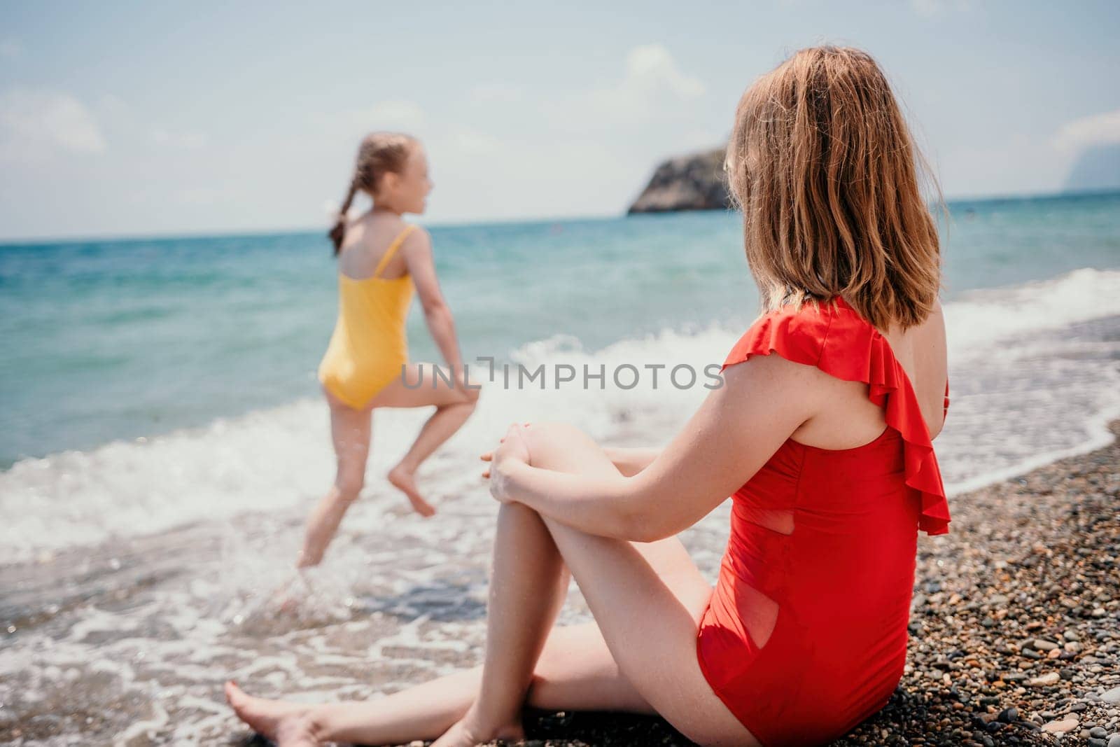 Happy loving family mother and daughter having fun together on the beach. Mum playing with her kid in holiday vacation next to the ocean - Family lifestyle and love concept.