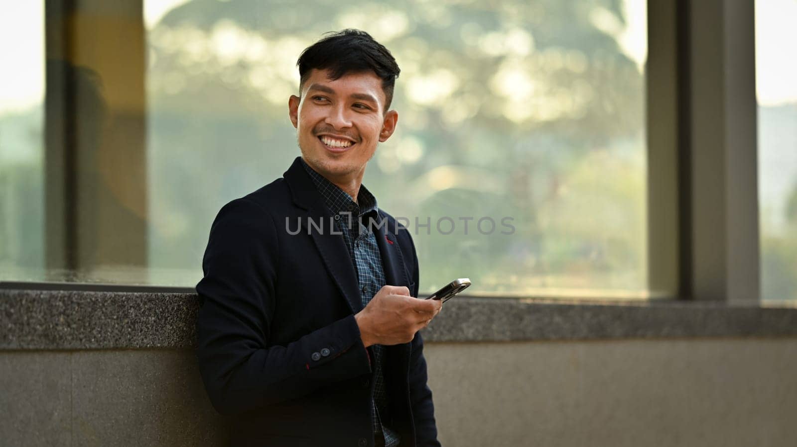 Portrait of businessman using mobile phone while sitting on bench outdoor. People, communication, technology.
