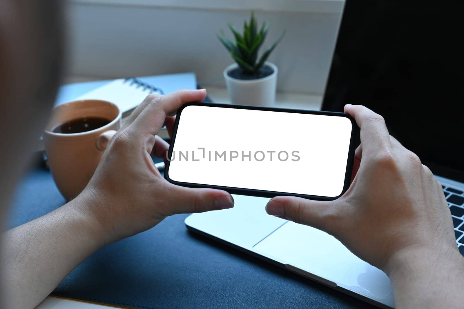 Man holding horizontal smart phone with white screen.