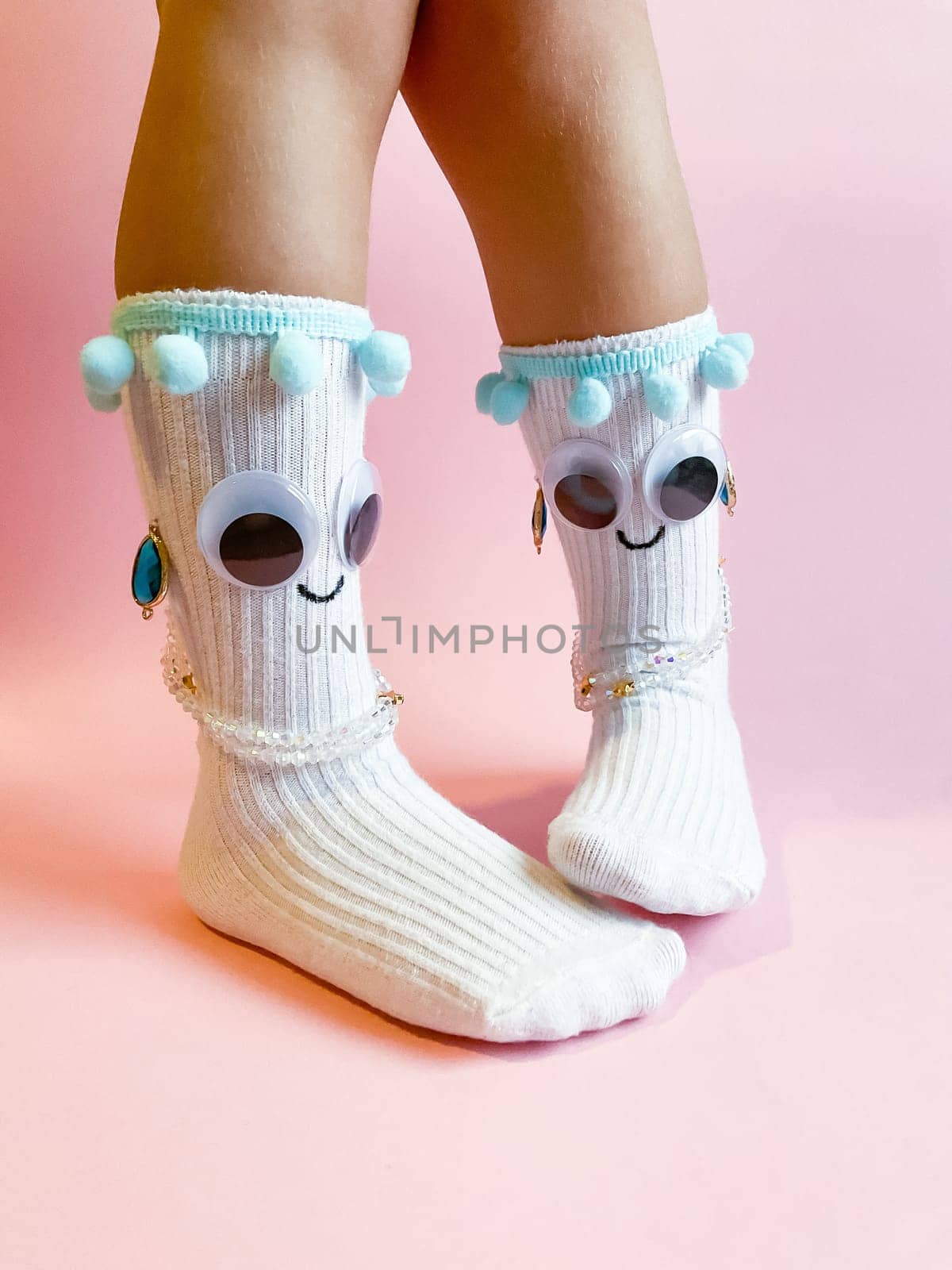 Baby socks with eyes and smile on pink background by Lunnica