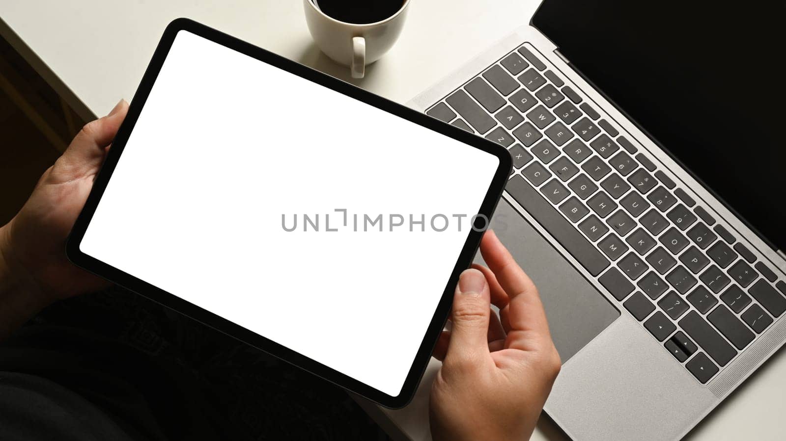Close up view of worker sitting at white office desk and using digital tablet. Blank screen for advertise text.