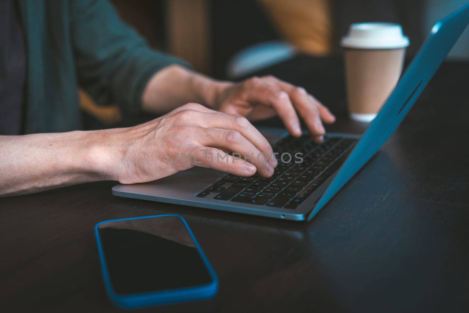 Close-up of man's hands typing text message on laptop keyboard. Work-from-home setup and modern communication technology. The man focused on task, with laptop screen out of focus in the background. High quality photo