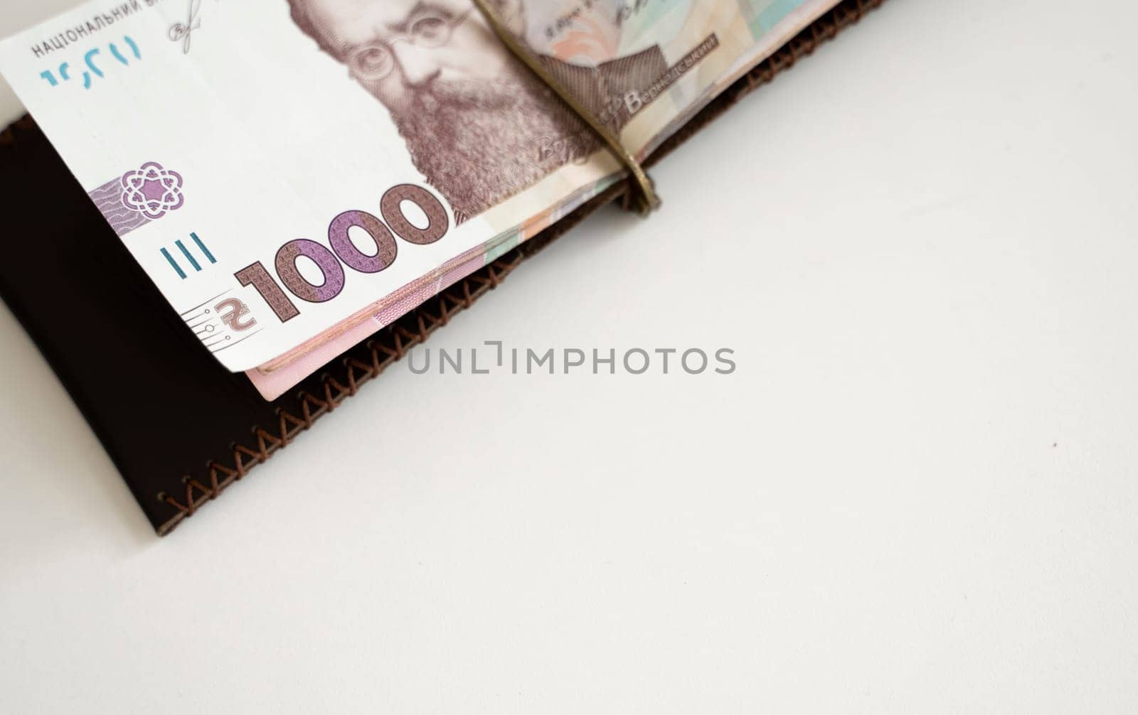 Brown leather money clip, purse with ukrainian hryvnia banknotes. Men's genuine leather wallet. Accessories. Money, financess, economy, saving