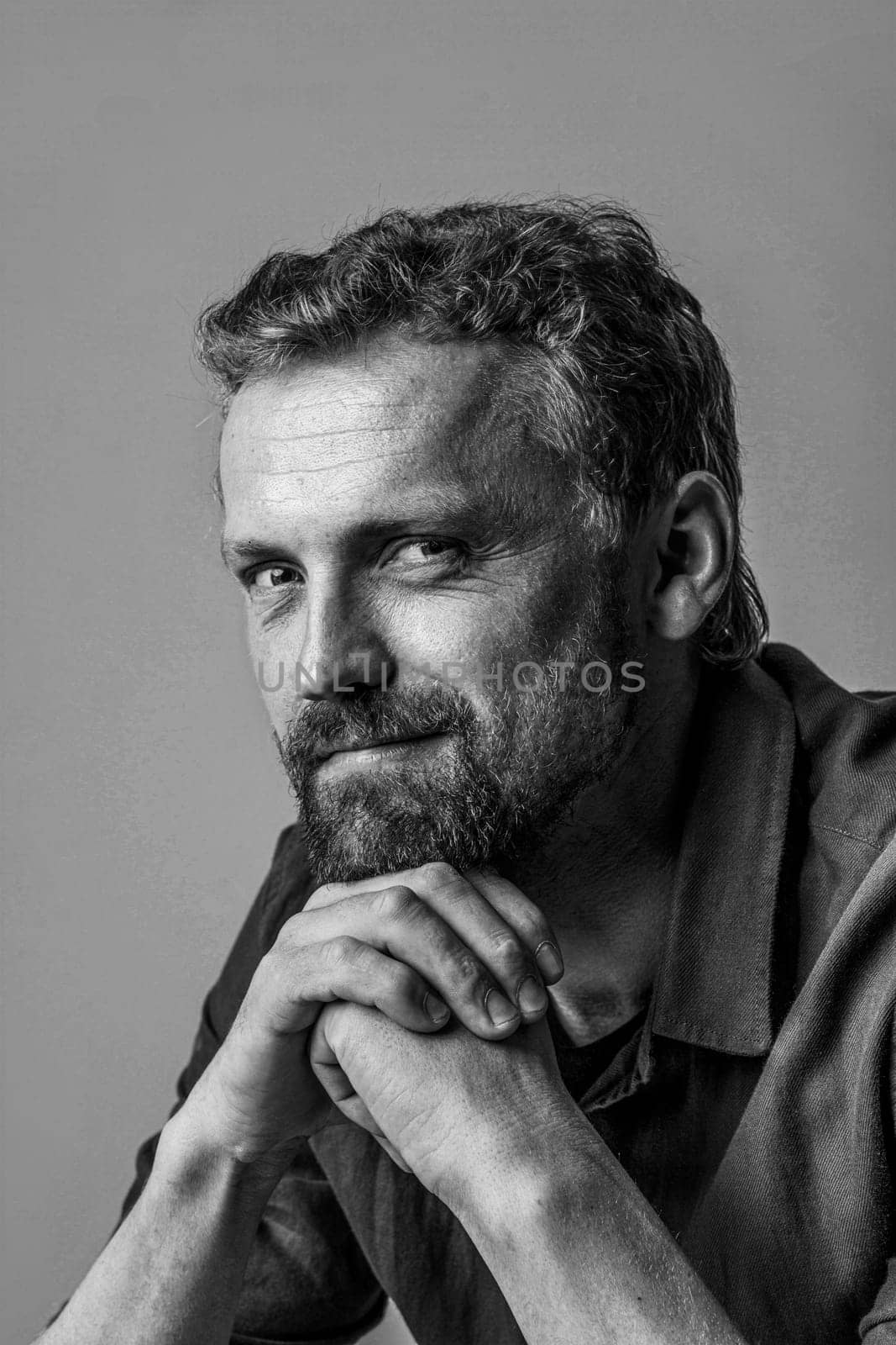 Cute and handsome caucasian man posing in photo studio with hands together. Black and white photo, with white background, making it versatile and timeless addition to any project. High quality photo