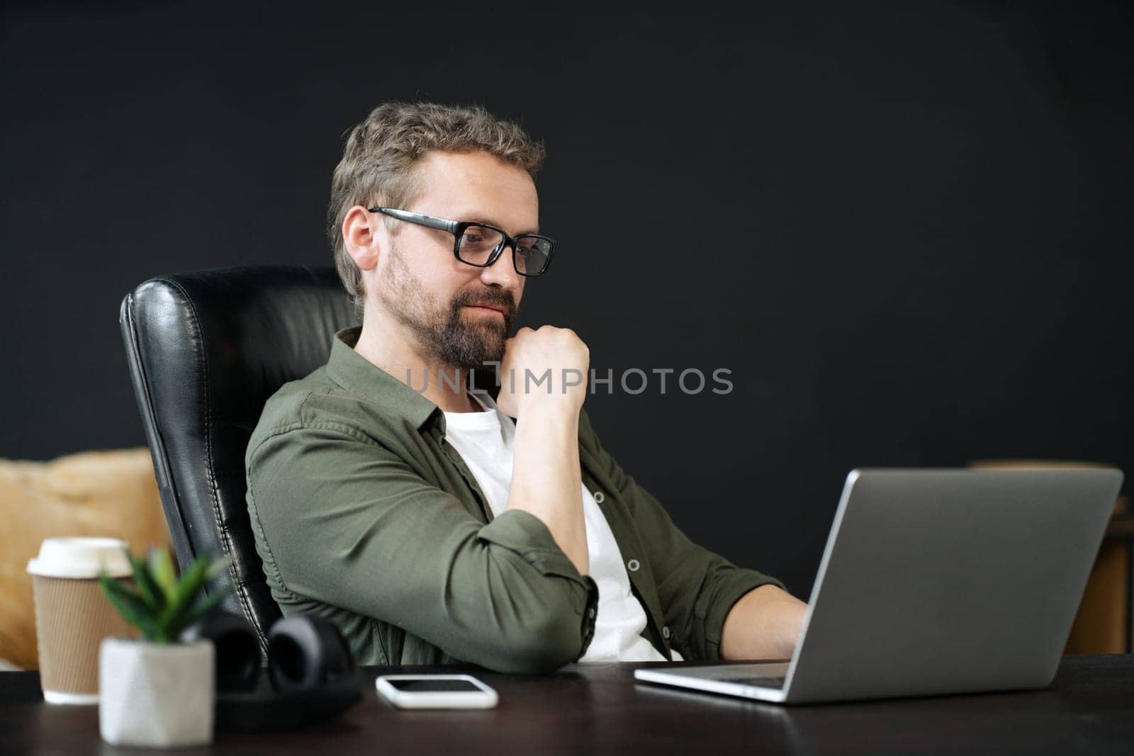 Wise, caucasian man captured in portrait, sitting at desk in home office. He appearing thoughtful, as he works on computer. Sense of professionalism and productivity in a home work environment. High quality photo