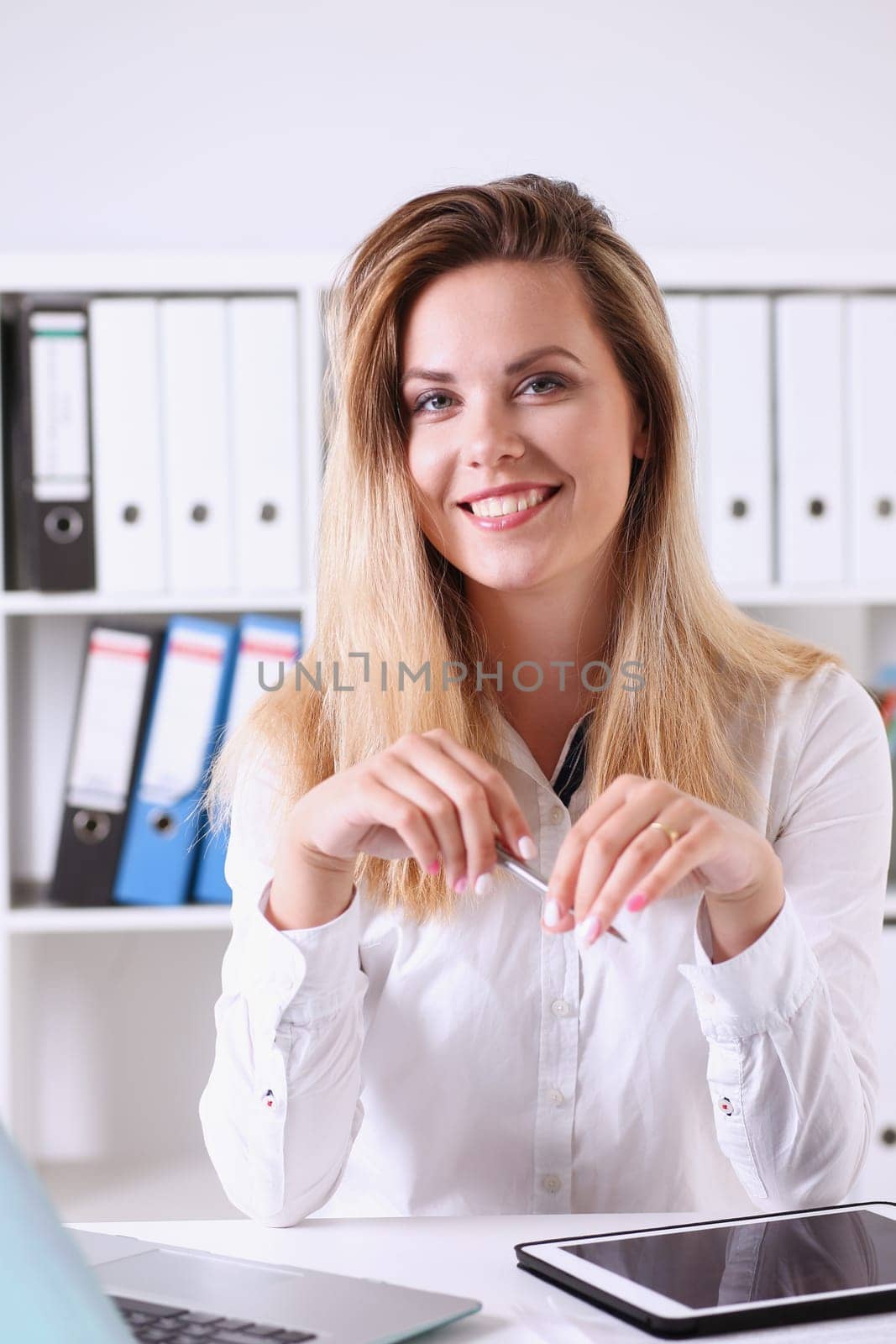 Beautiful businesswoman portrait in office sitting at table smiling and looking at camera teacher expresses success checking control papers