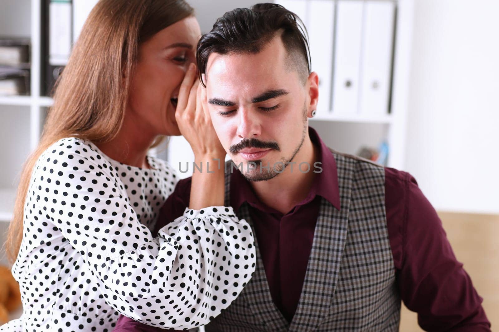Woman gossip whispers in the ear of news to a man in office