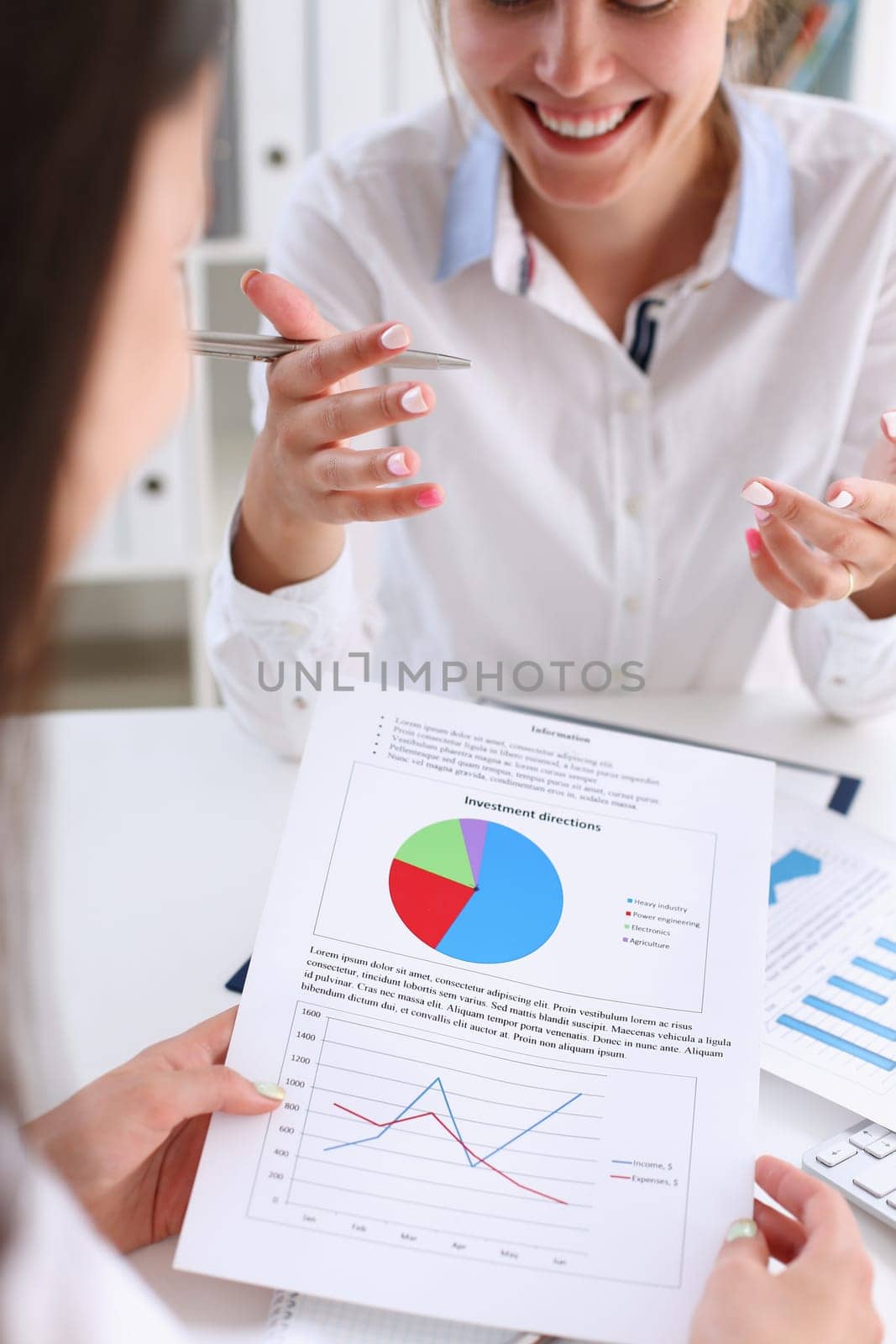 Businesswoman holding a silvery pen in her hand indicates the interlocutor for a digram on the form of annual report on the financing of organizations trains the processing of this statistical study.