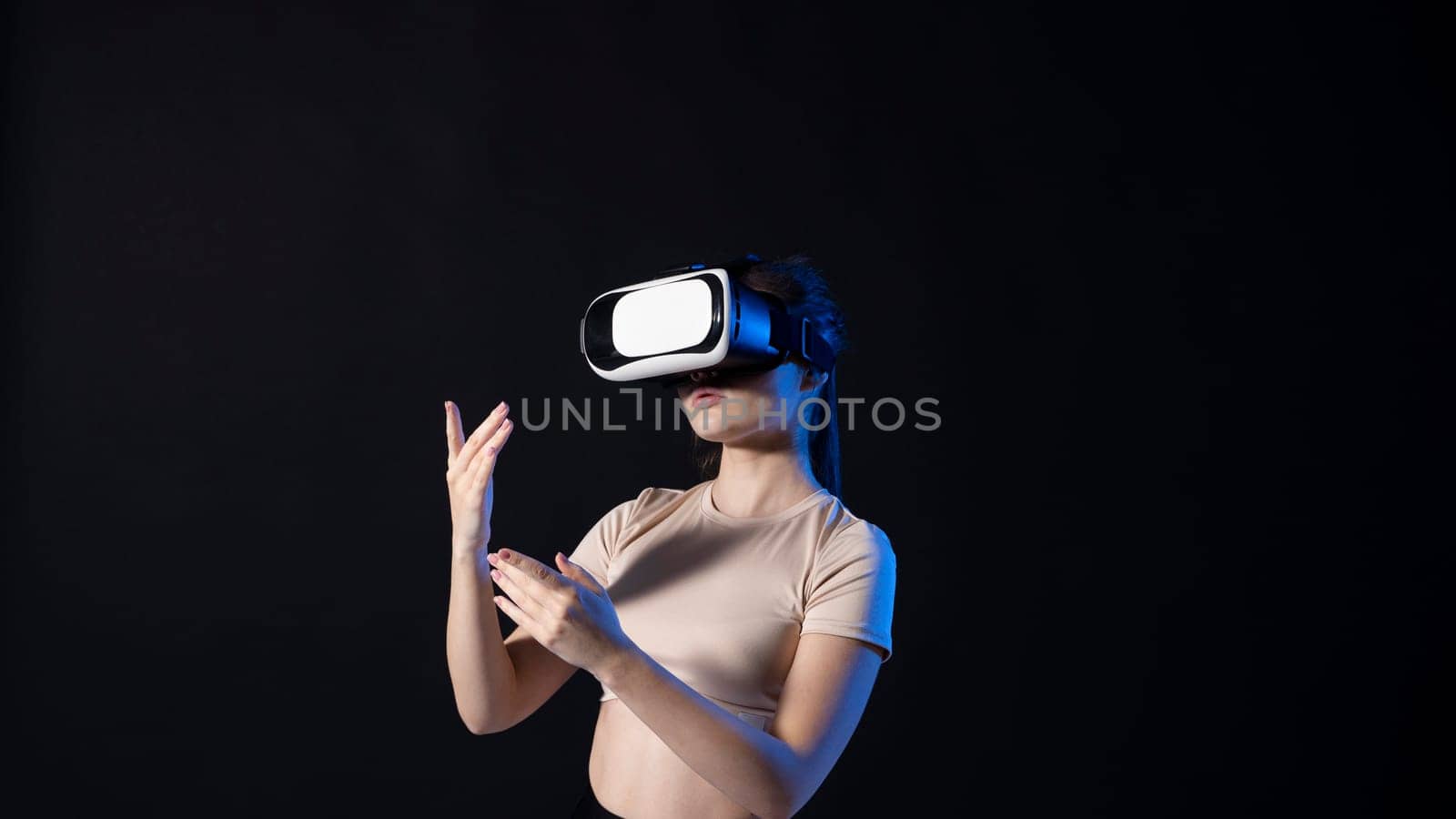 Portrait of young woman playing in VR-glasses in neon light on blue background. Concept modern gadgets and technologies. Future technology concept. Virtual reality gaming. by vovsht