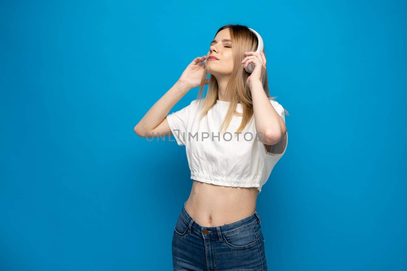 Portraite of lovely cheerful girl listening music isolated over bright blue color background. by vovsht